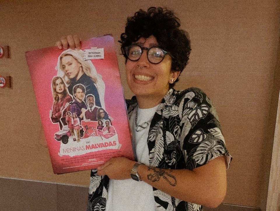 Foto kinha sorrindo segurando um posterzinho A3 do filme Meninas Malvadas, o musical