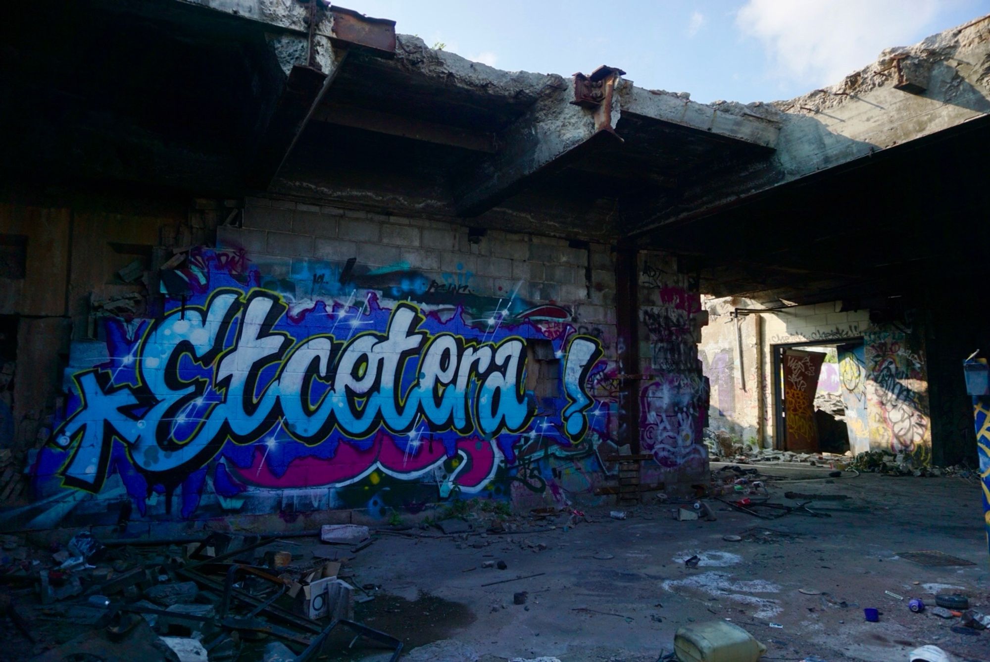 Graffiti that says Etcetera in an abandoned warehouse with missing roof.