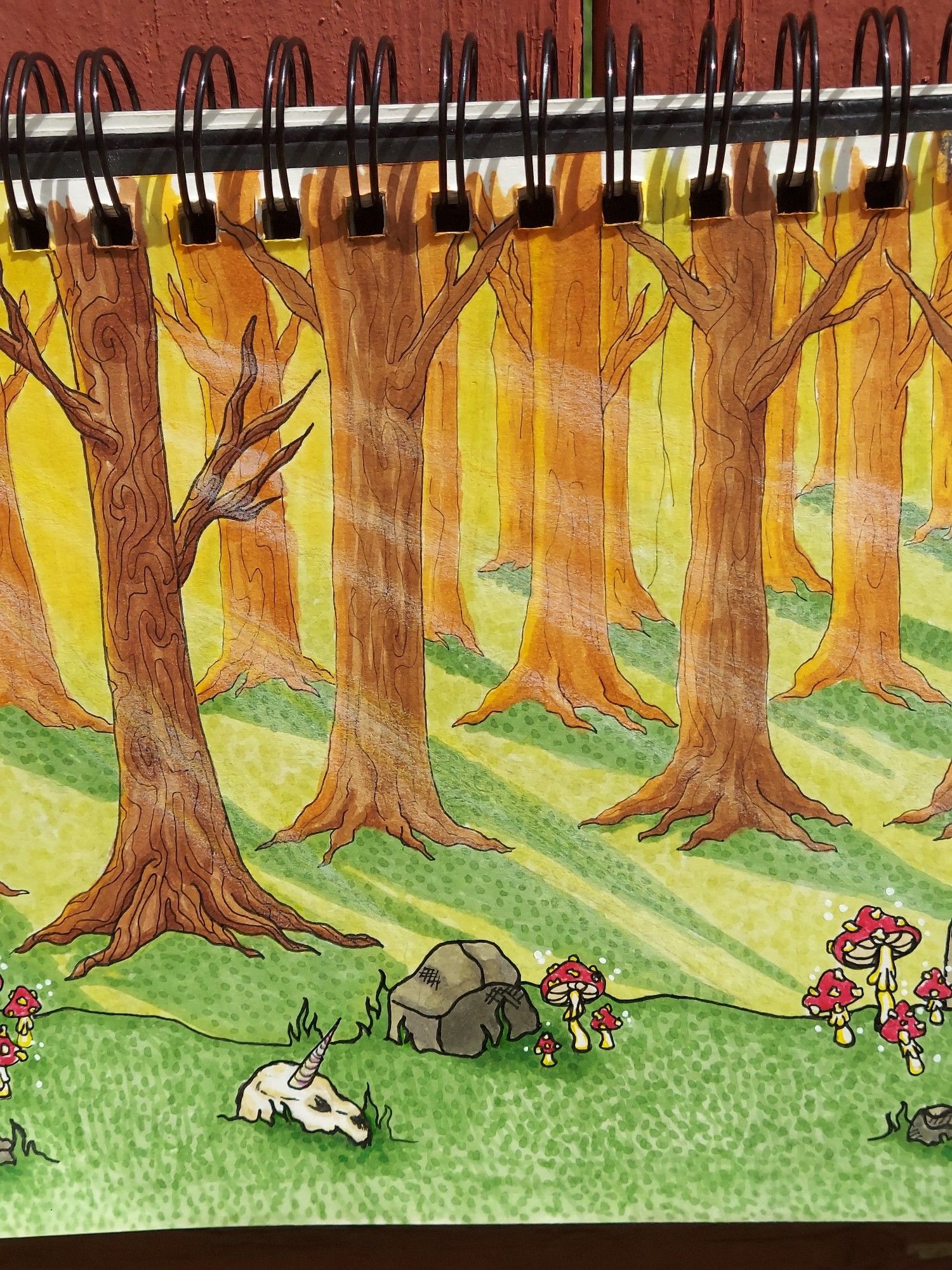 A color  drawing of an enchanted forest with red capped mushrooms and a unicorn skull on the forest floor.  Sunlight is beaming through the trees.