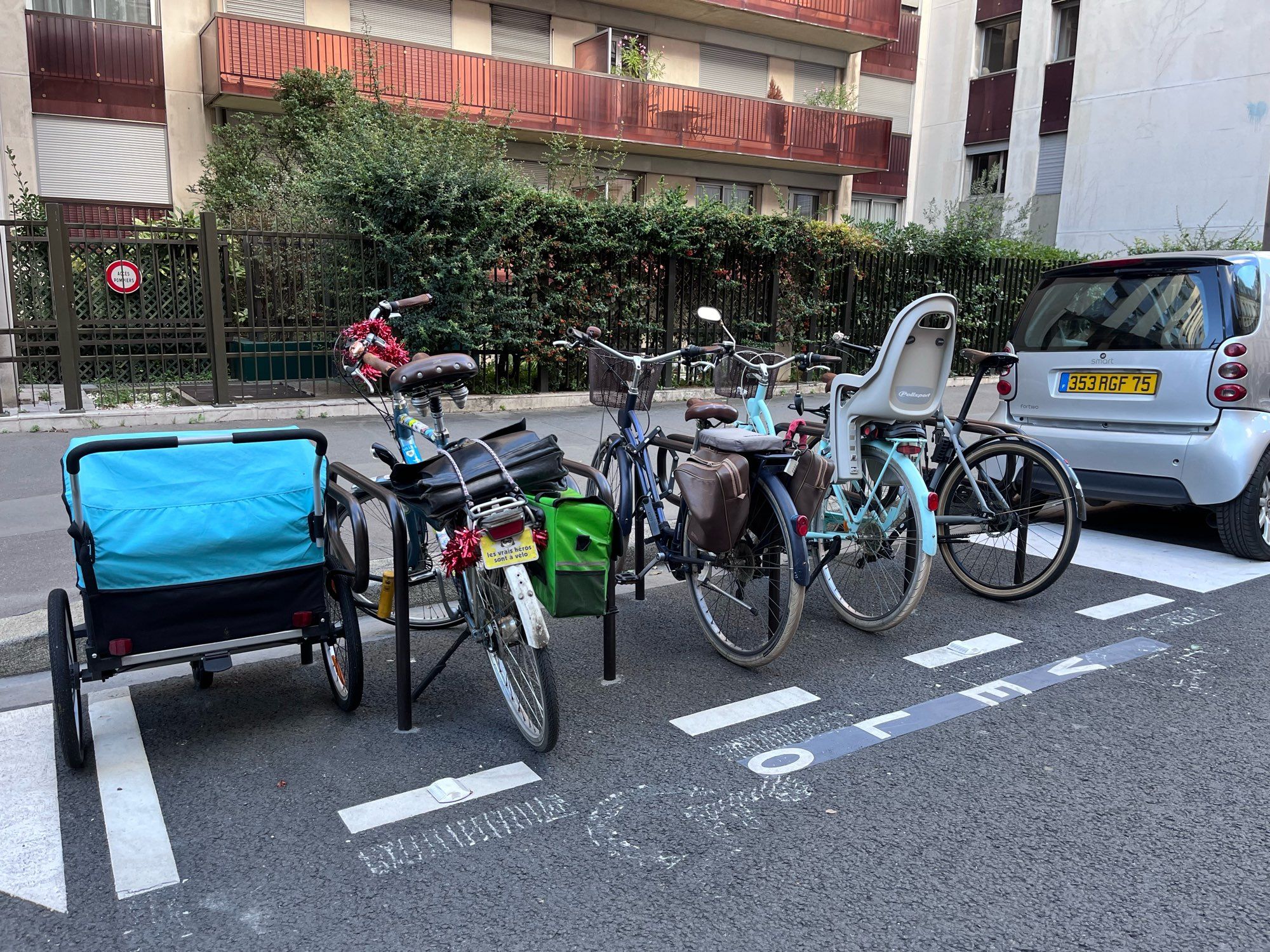 Une remorque vélo bleue garée sur un parking vélo.