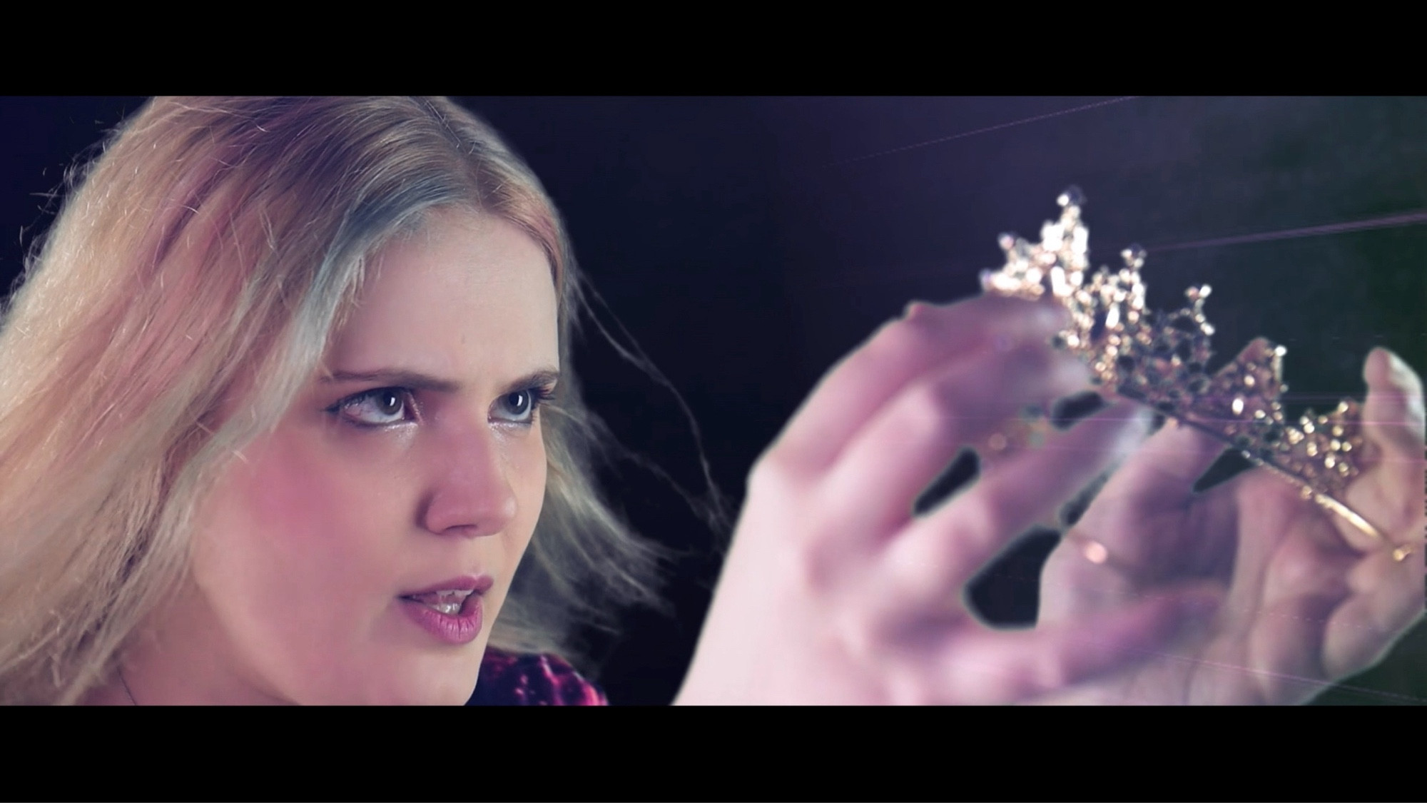 Tara holding a crown menacingly (screenshot from WIP youtube music video)