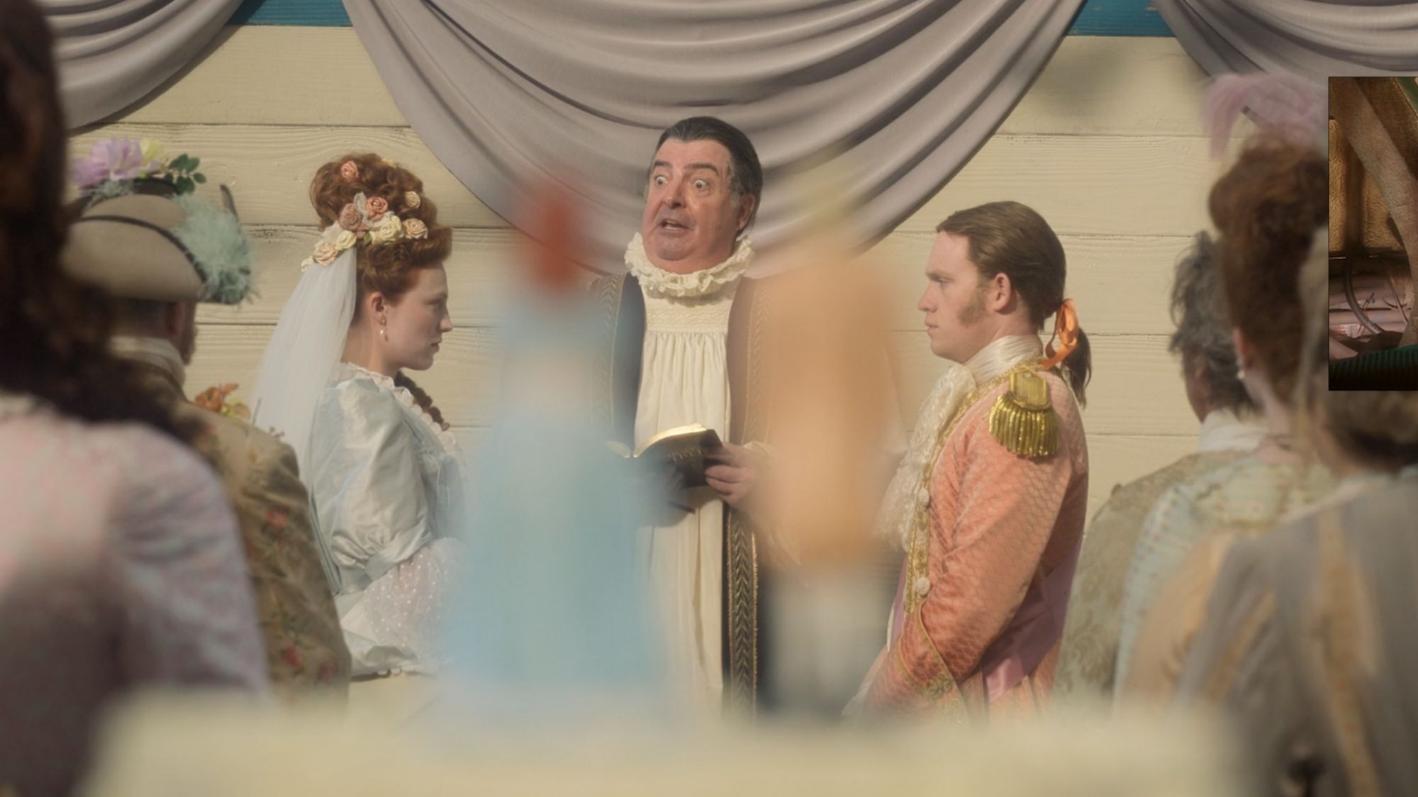 The wedding toppers sit unfocused in the foreground while the bride and groom are in the background.