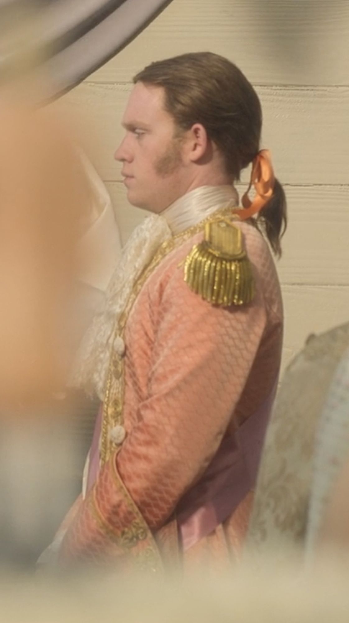 Close up of the groom in his orange fish-scaled suitm.