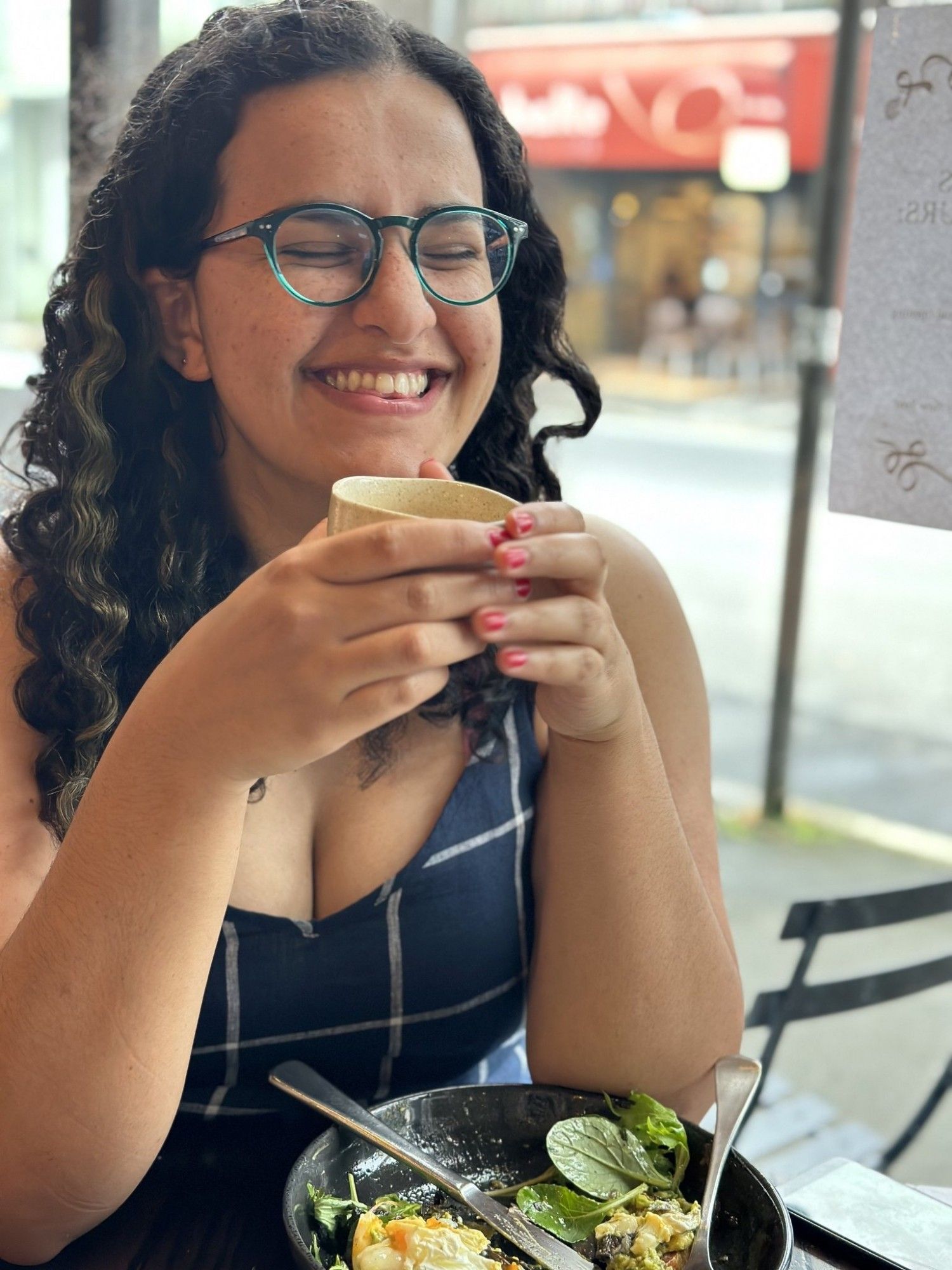 An image of the author, a mixed race brown skinned woman with curly hair, smiling her entire face off!