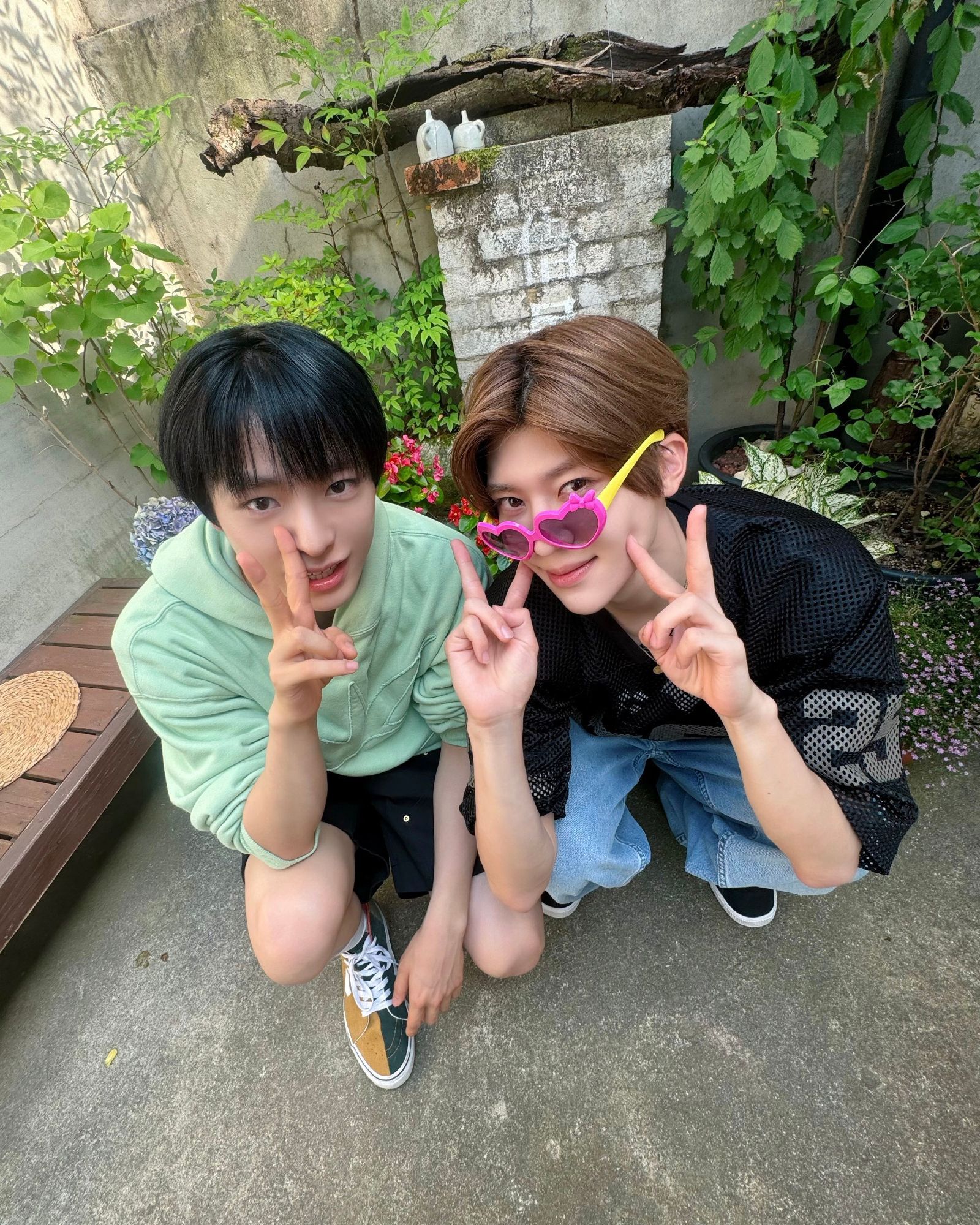 the next two are adorable photos of yushi and sion in the same mint and black outfits but now they're squatting outside and throwing peace signs at the camera. sion also has plastic toy pink and yellow heart shades on