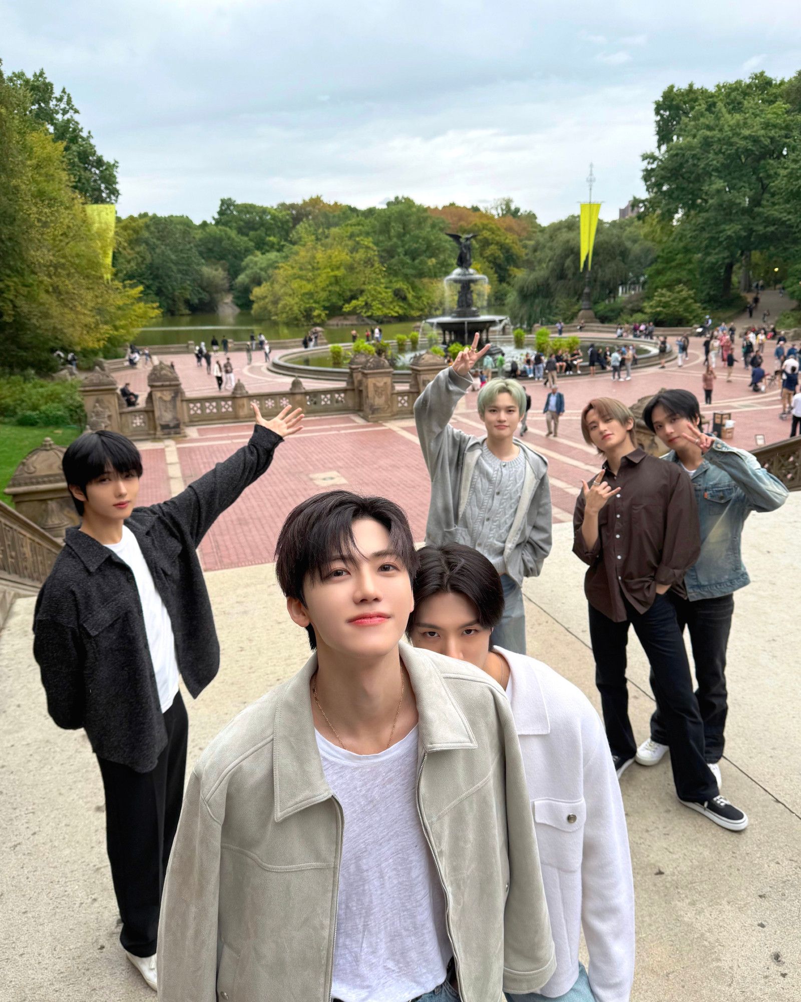 cutie patooties nct dream out for a stroll in central park and taking a very cute group photo. left to right, from the back: jisung, chenle, mark, haechan, jaemin, and jeno