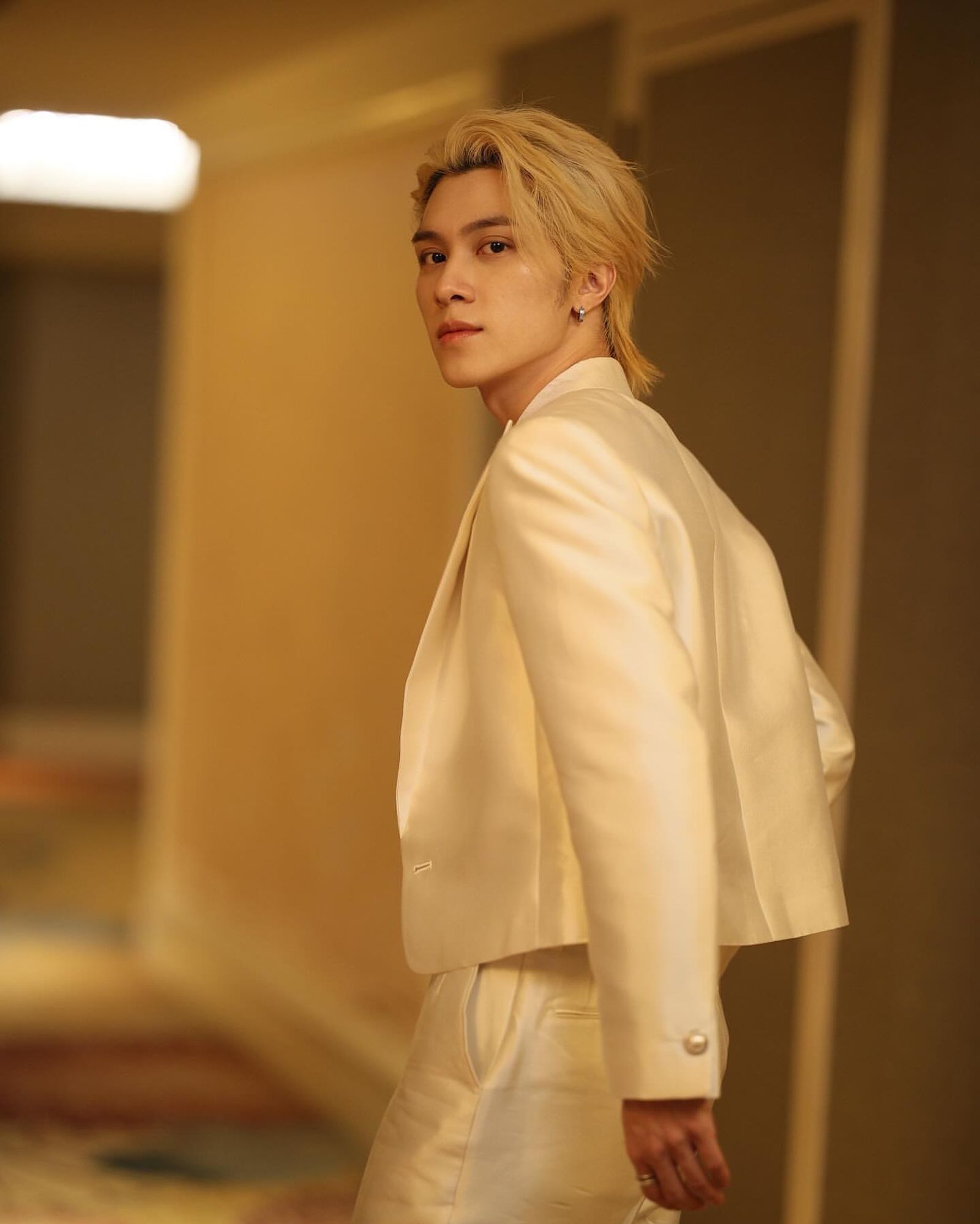 gorgeous photo of hendery looking back at the camera wearing a prince-like white suit and blonde hair