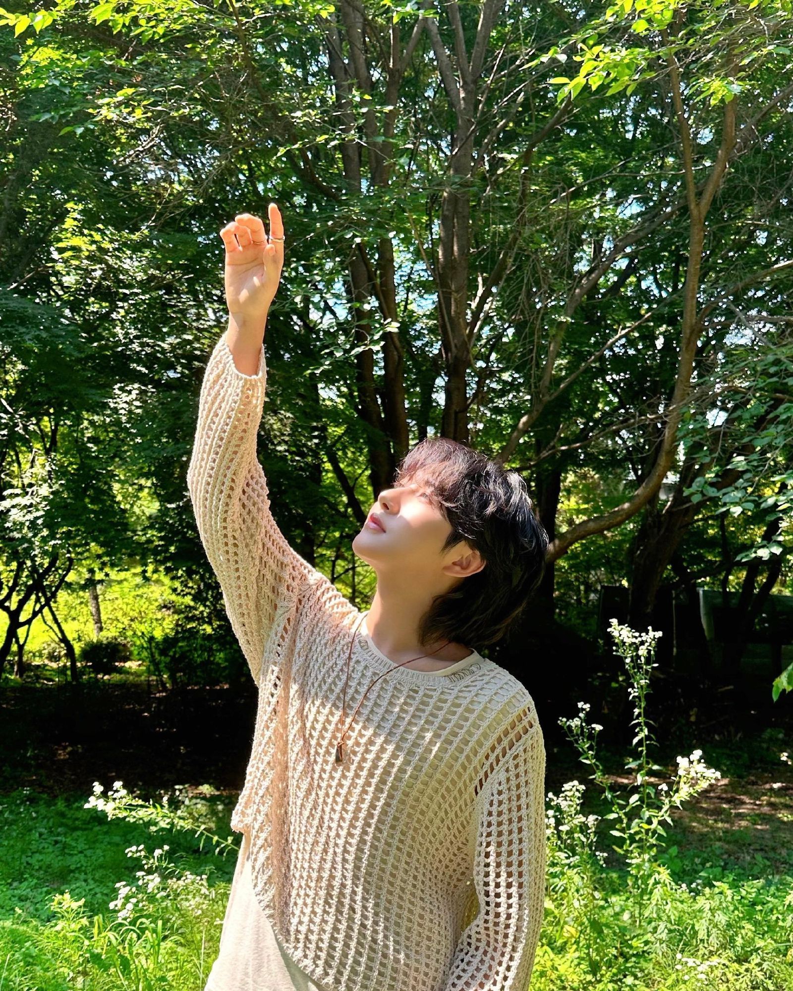 gorgeous beautiful behind the scenes photo of renjun for 'rains in heaven' wearing a beige sweater and holding his hand up to the sun