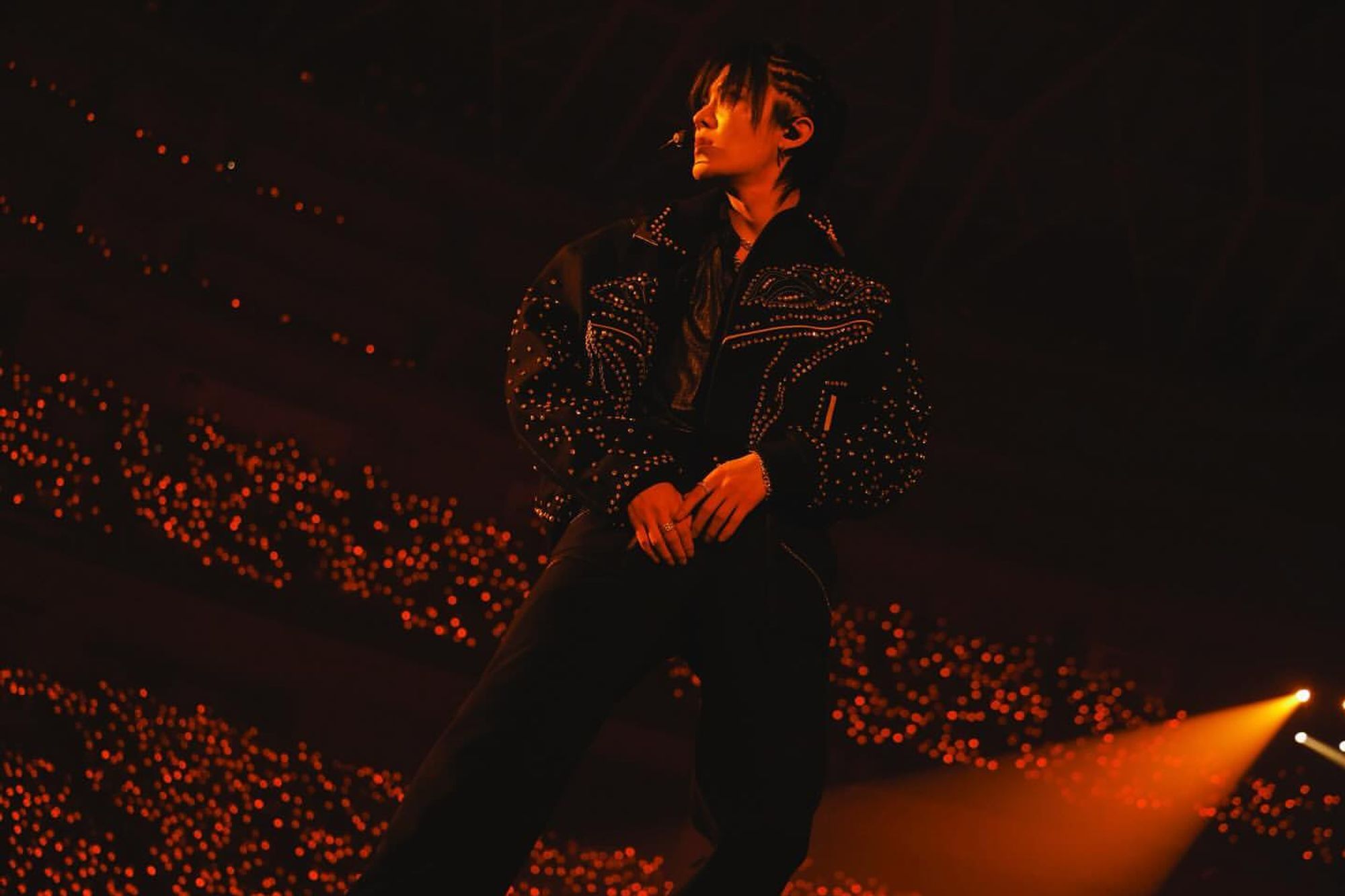 amazingly cool looking yuta in his black concert outfit on stage bathed in red orange lighting