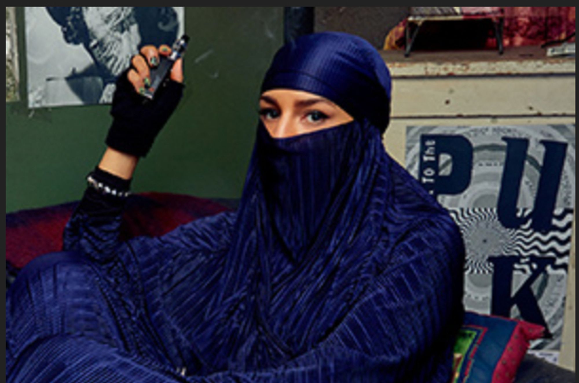 Momtaz, a character from "We Are Ladyparts," wearing a privacy-preserving royal blue niqab and holding a vape pen.