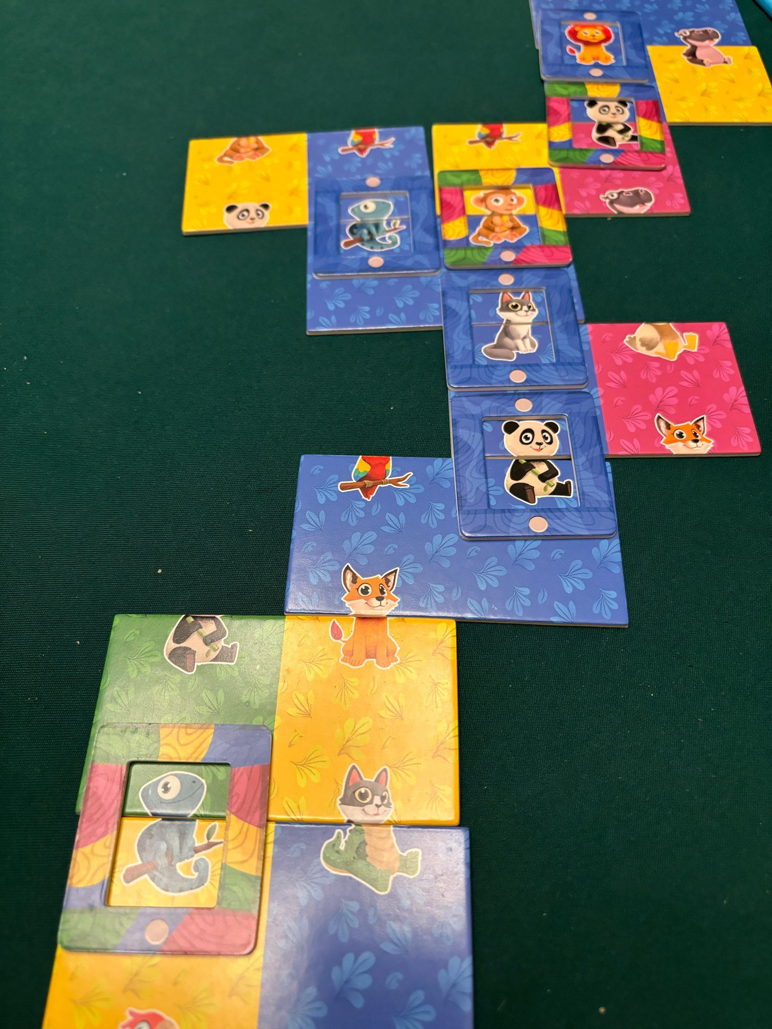 Zoomino board game. Colorful domino cardboard tiles with animal heads and bodies on them. Some are connected together with cardboard frames over them.