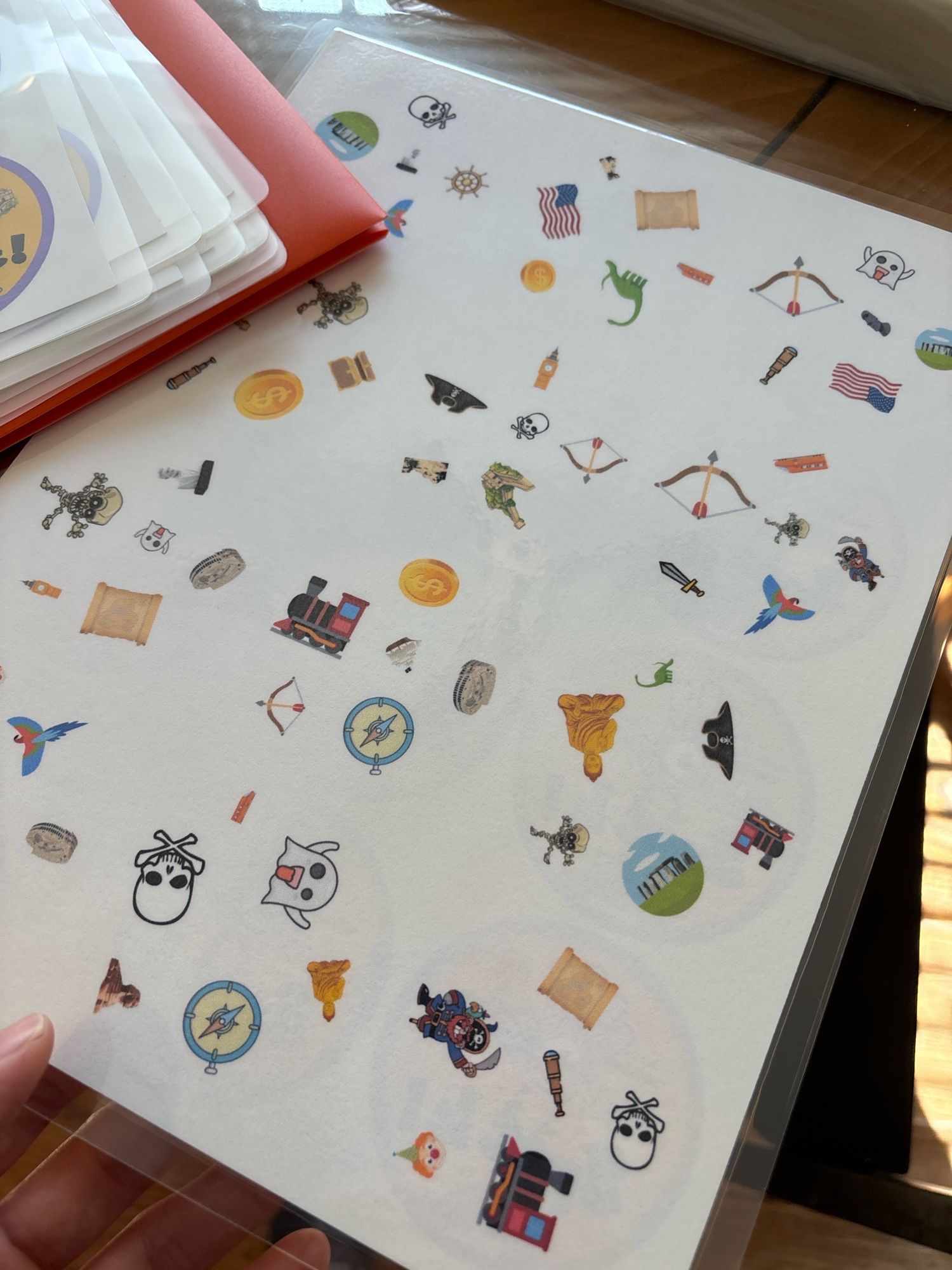 Laminated paper with a bunch of symbols on it in circles like the game Spot it! (Dobble)
Icons include pirate things, skeletons, trains, and monuments.