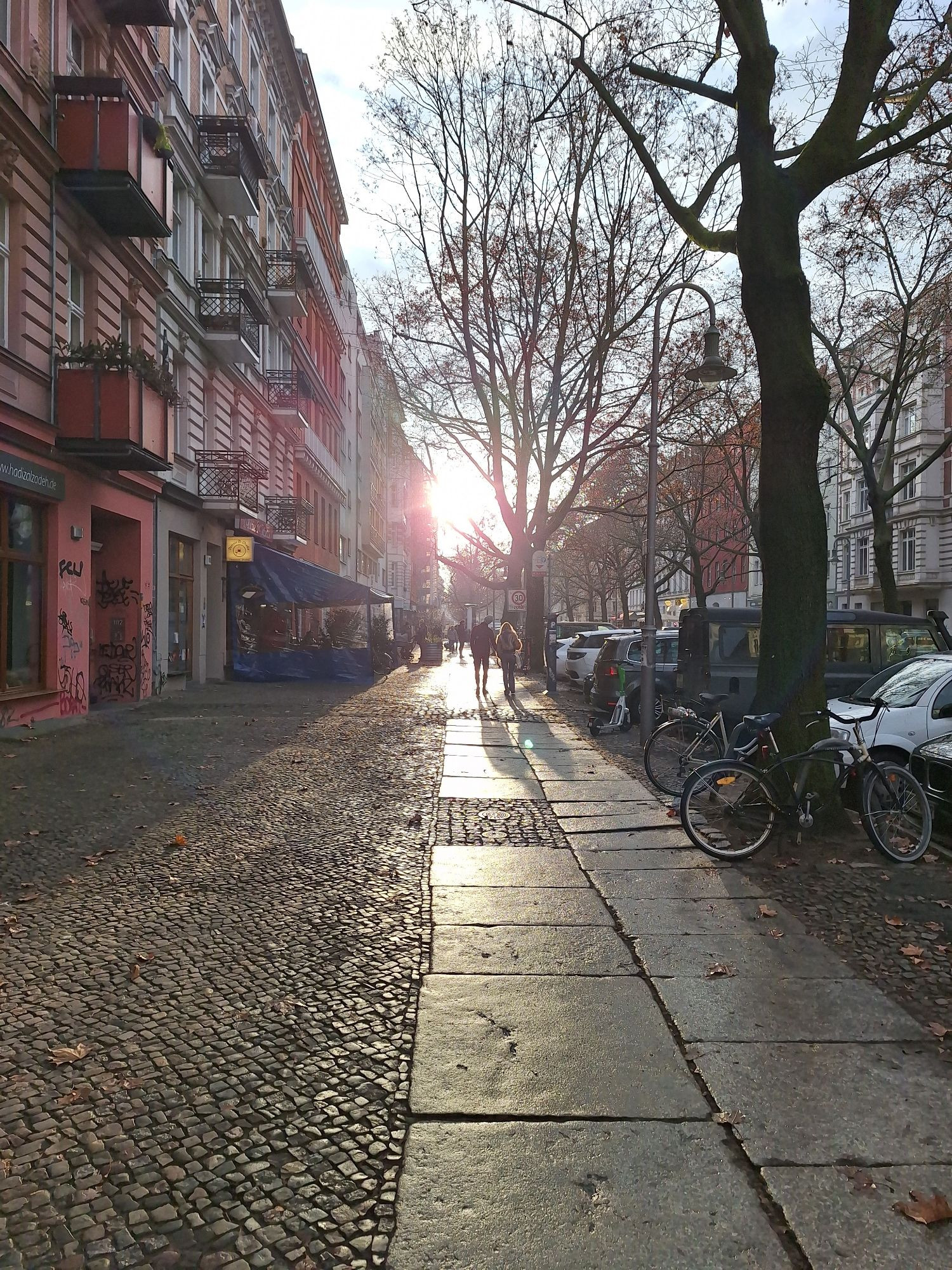 Straßenansicht. Sonne, die durch graue Wolken hindurch strahlt und auf dem Gehweg reflektiert