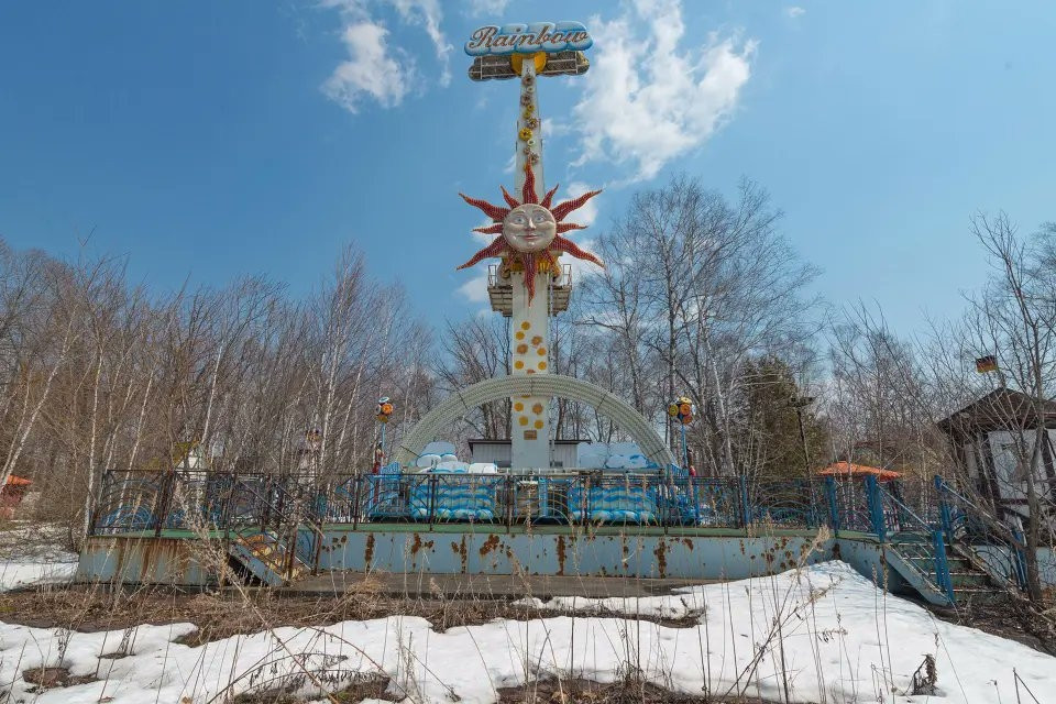 Photograph of an abandoned fairground ride in the snow.