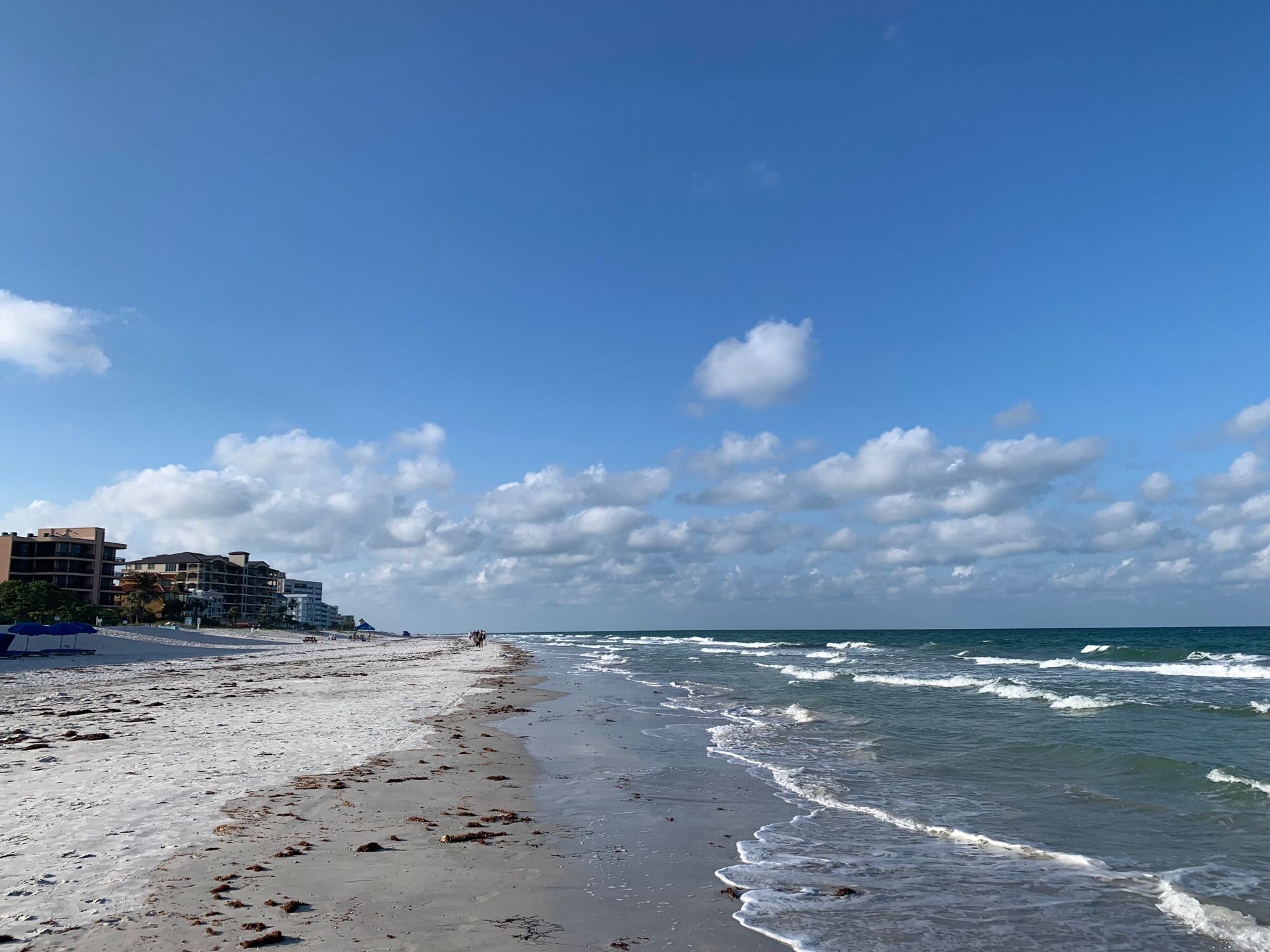 A May 2024 picture from Gulf coast beach called Indian Shores in Florida. Waves gently rolling in. Beyond the beach condos are seen. Since this the area has been hit by several hurricanes…