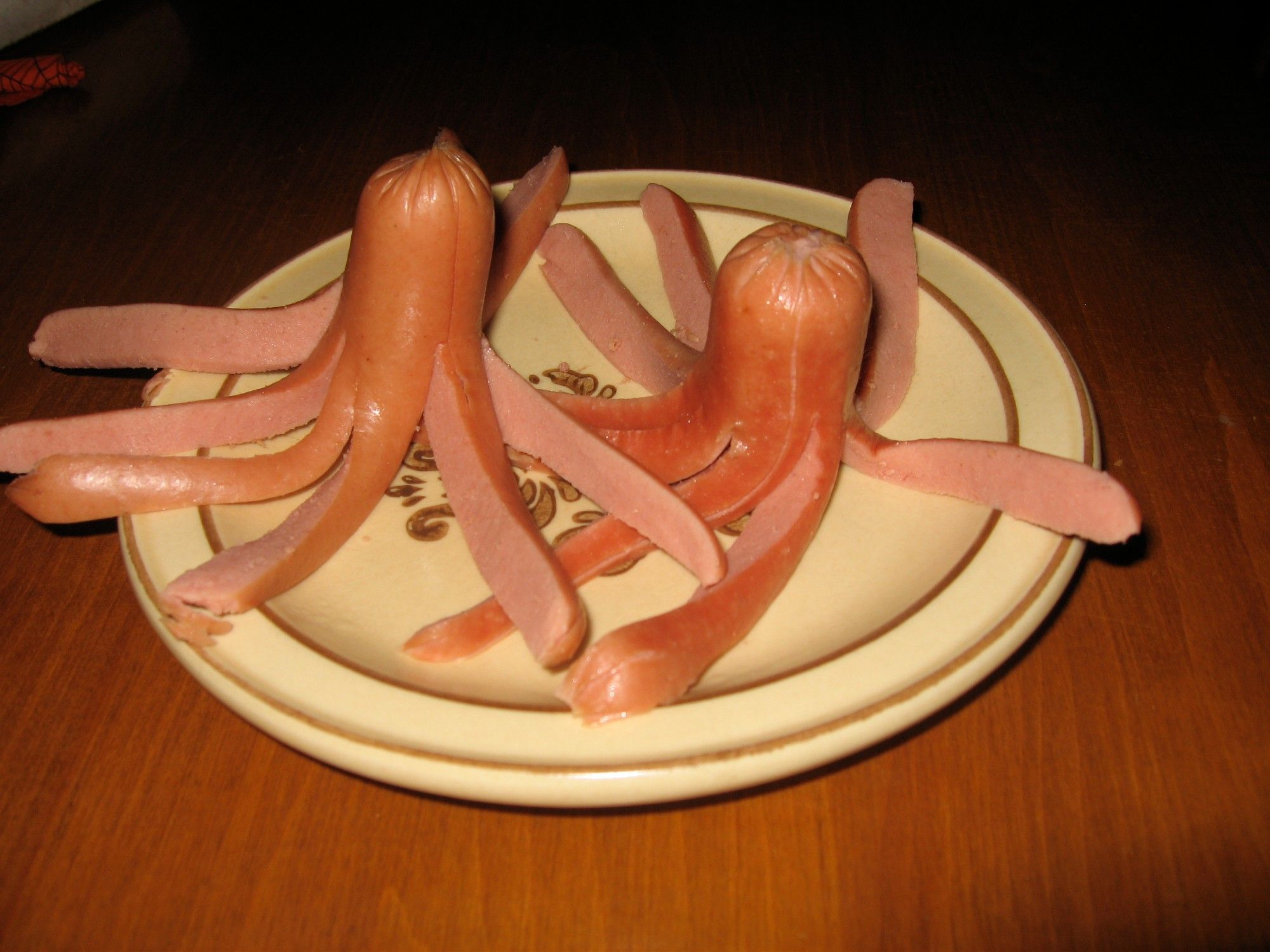 Two hot dogs on a small plate, with one end bisected into 8 long strips to look like the tentacles of an octopus: a hotdogtopi.