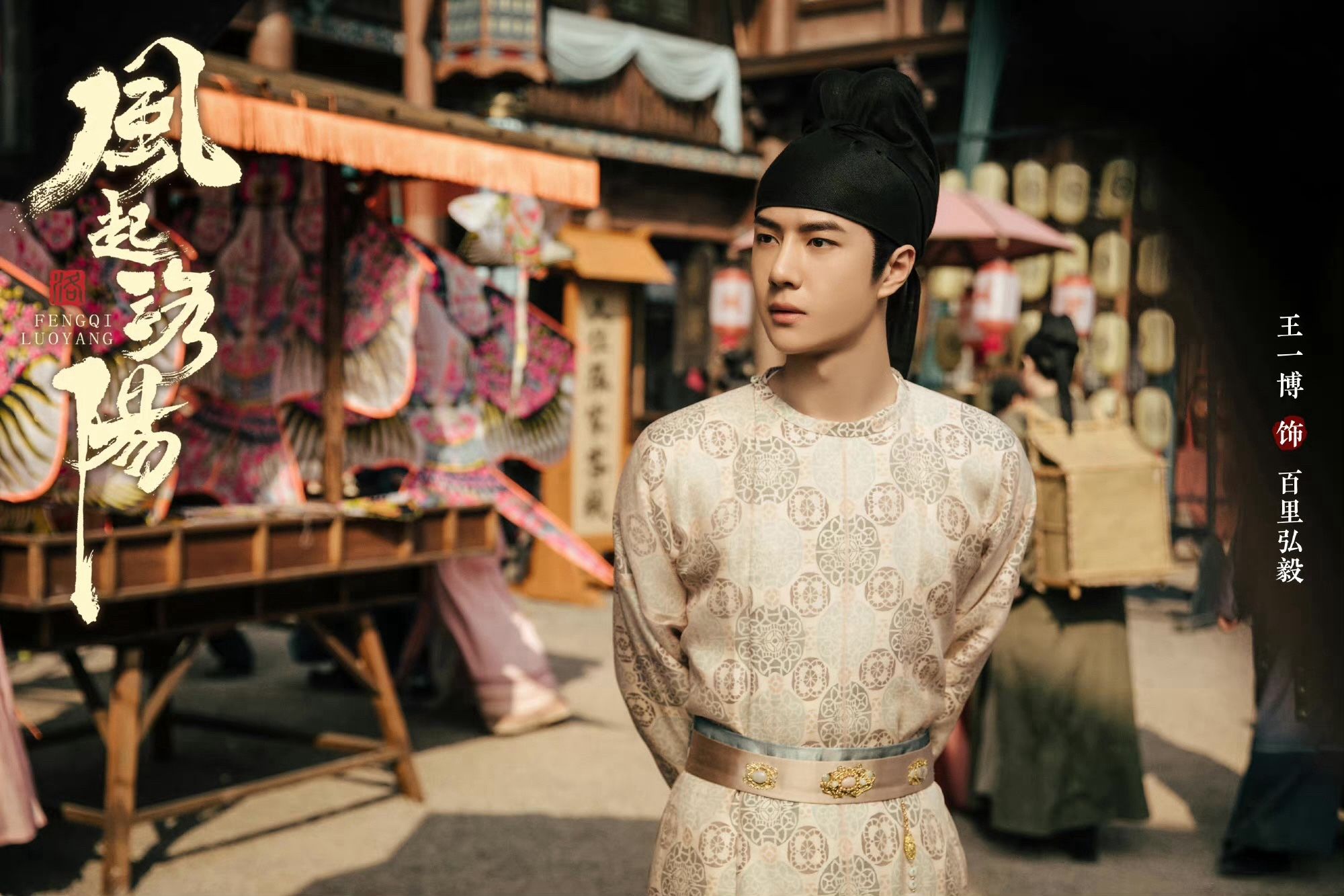 Wang Yibo dressed in costume drama from drama Luoyang, walking on a busy street. He is wearing a beige with gold color robe and black top typical from tang dynasty.