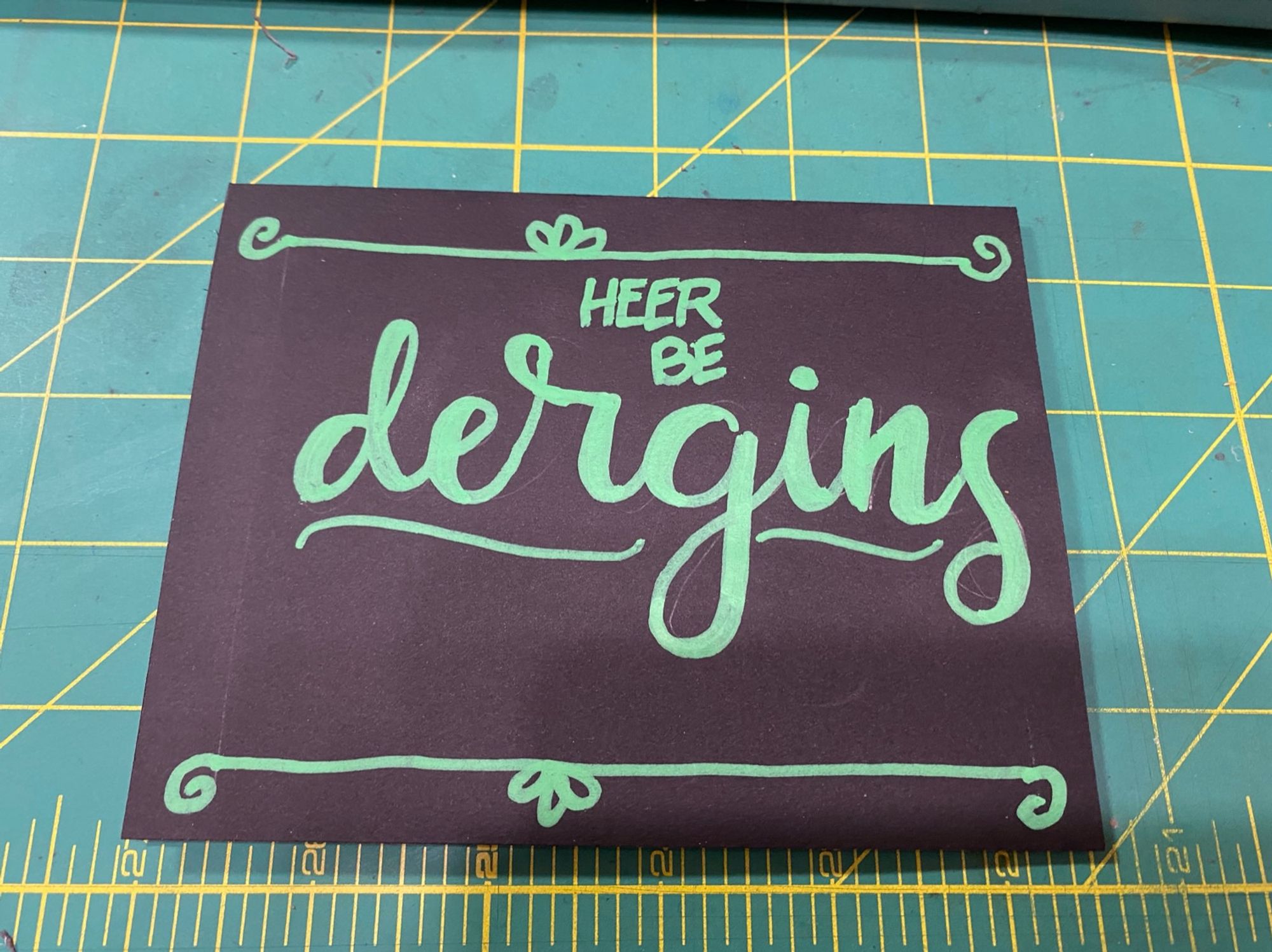 A piece of cardstock with lettering that says “heer be dergins”