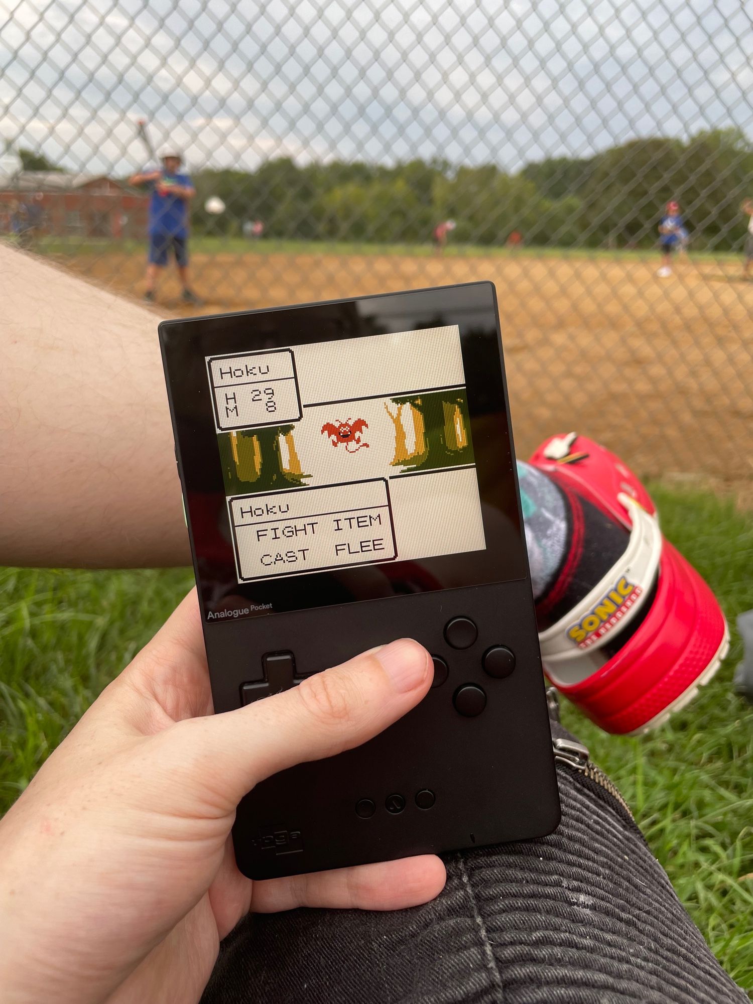 Playing dragon quest on an analogue pocket at a baseball field