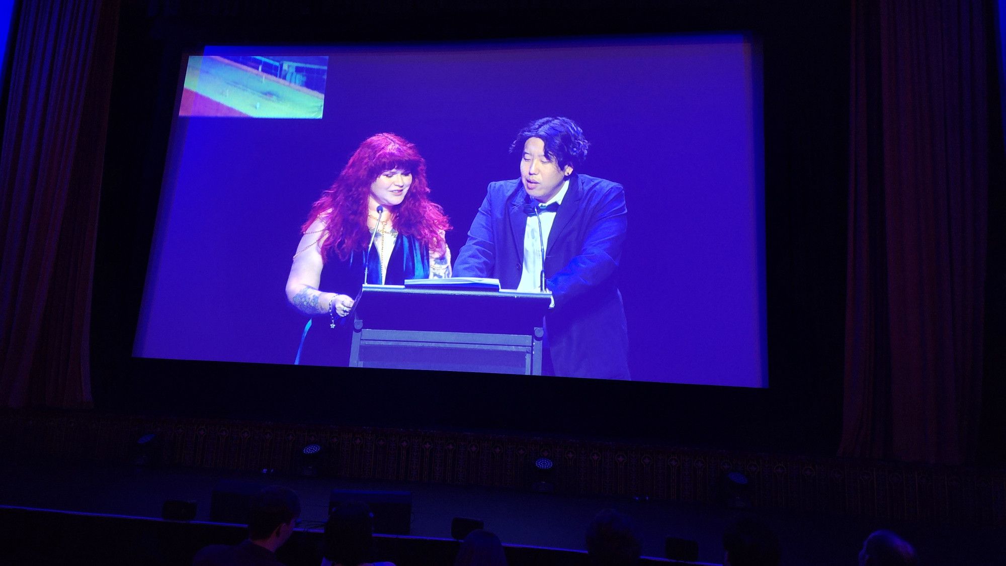 Photo of a screen showing the two hosts presenting for the AGDAs 2024: Gemma Driscoll and Harry Jun. They were fun! Accidentally revealed the GOTY award winner before the nominees were all announced tho, whoops!