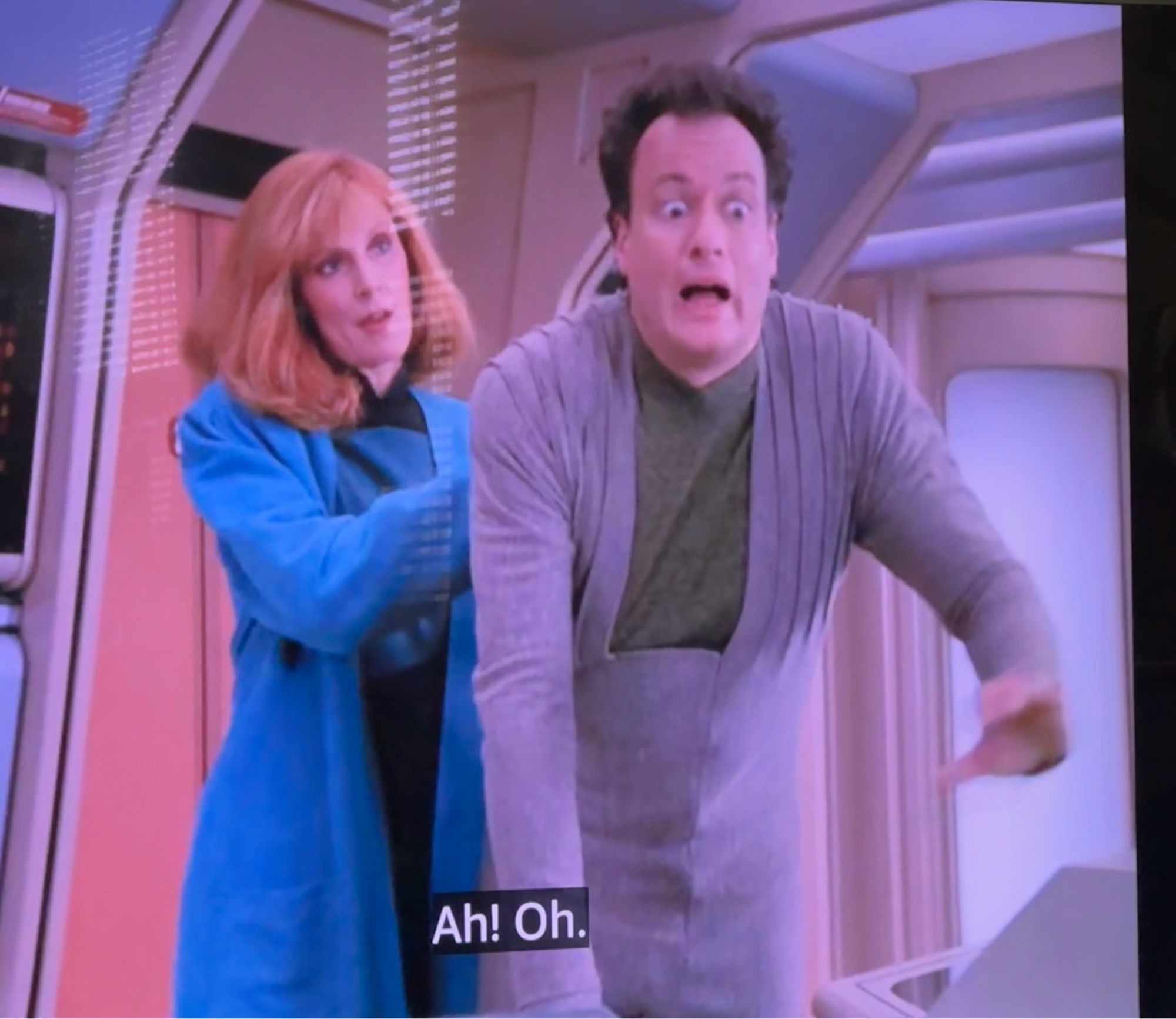 Crusher doing something from behind to Q. Bev has a satisfied look on her face while Q is experiencing some shocking pleasure. She’s “fixing his back” I think the episode said.