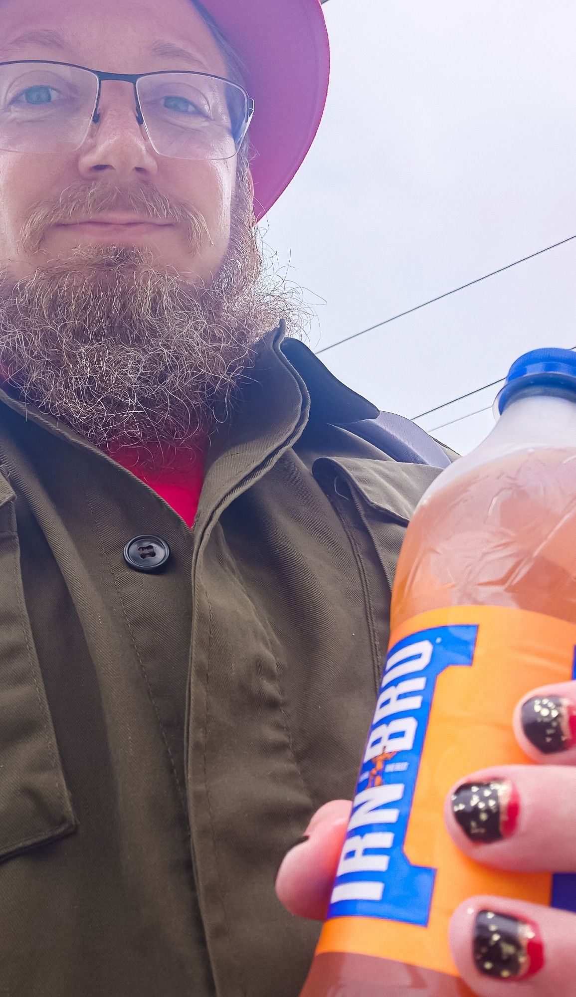 Me holding a bottle of irn bru while i wear a green jacket and red shirt