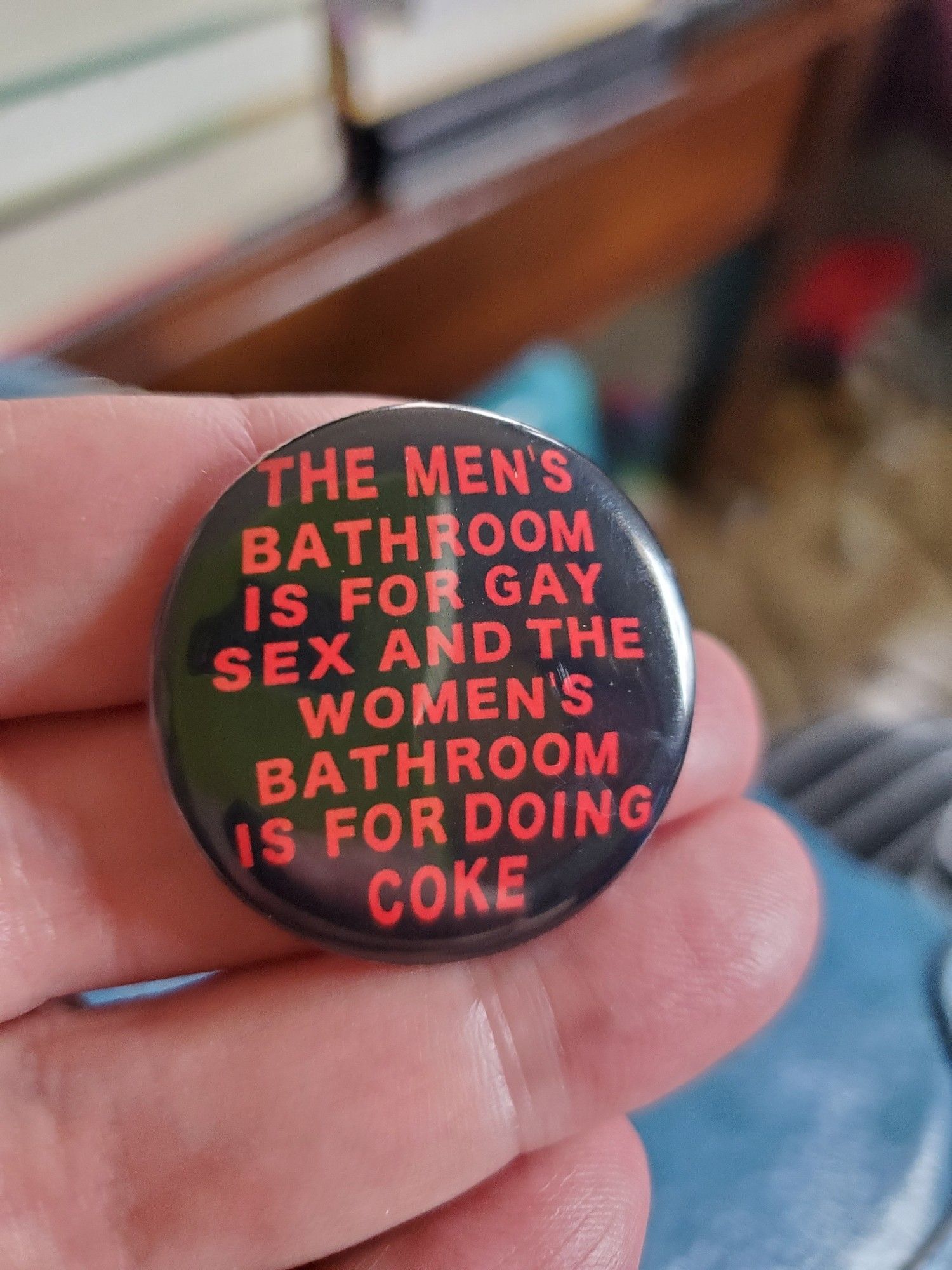 A pin that reads: the men's bathroom is for gay sex and the women's bathroom is for doing coke.