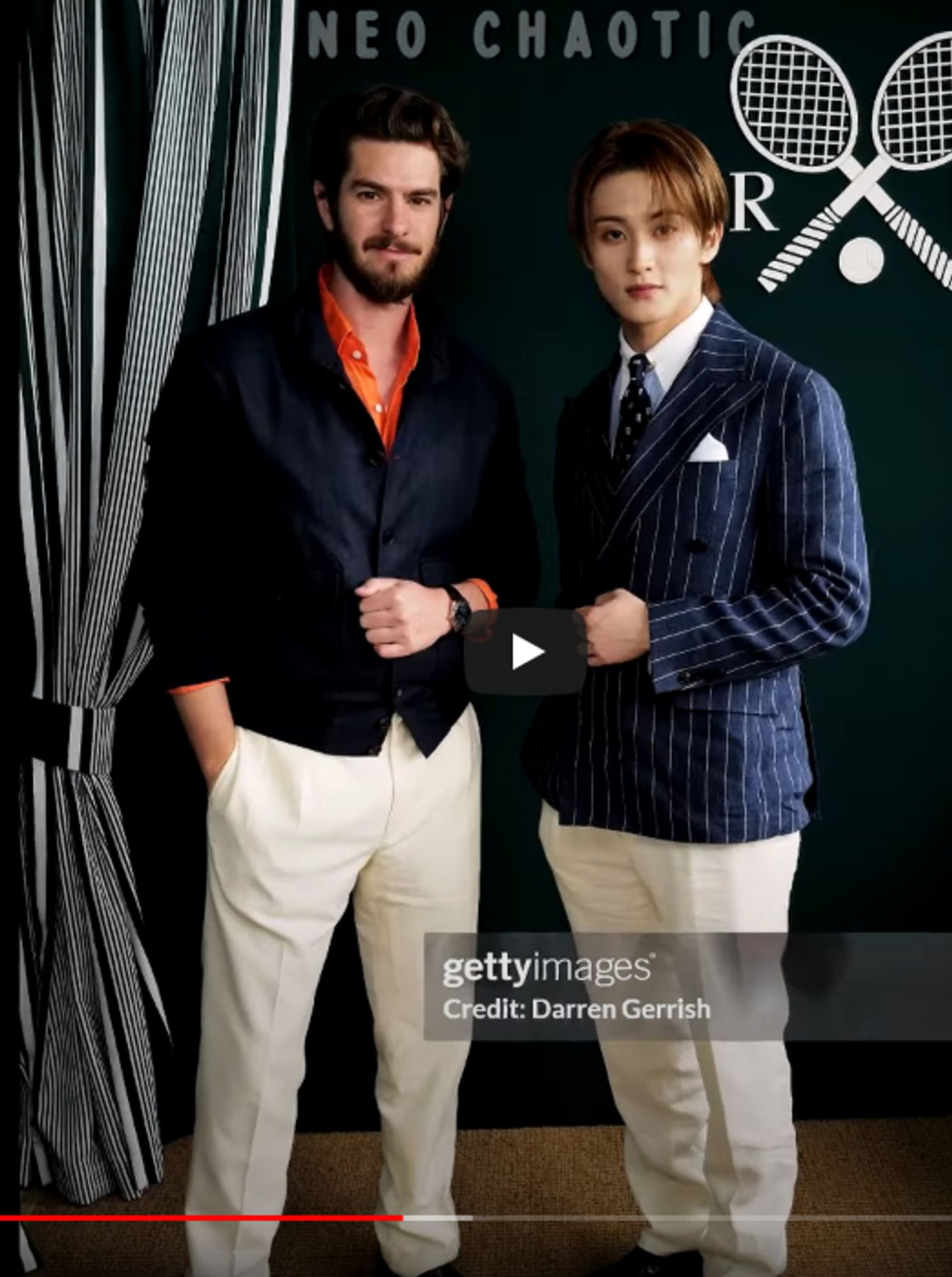 Mark Lee in the same pinstripe suit, posing with Andrew Garfield, who is dressed in khakis, a navy blue blazer, and a red shirt