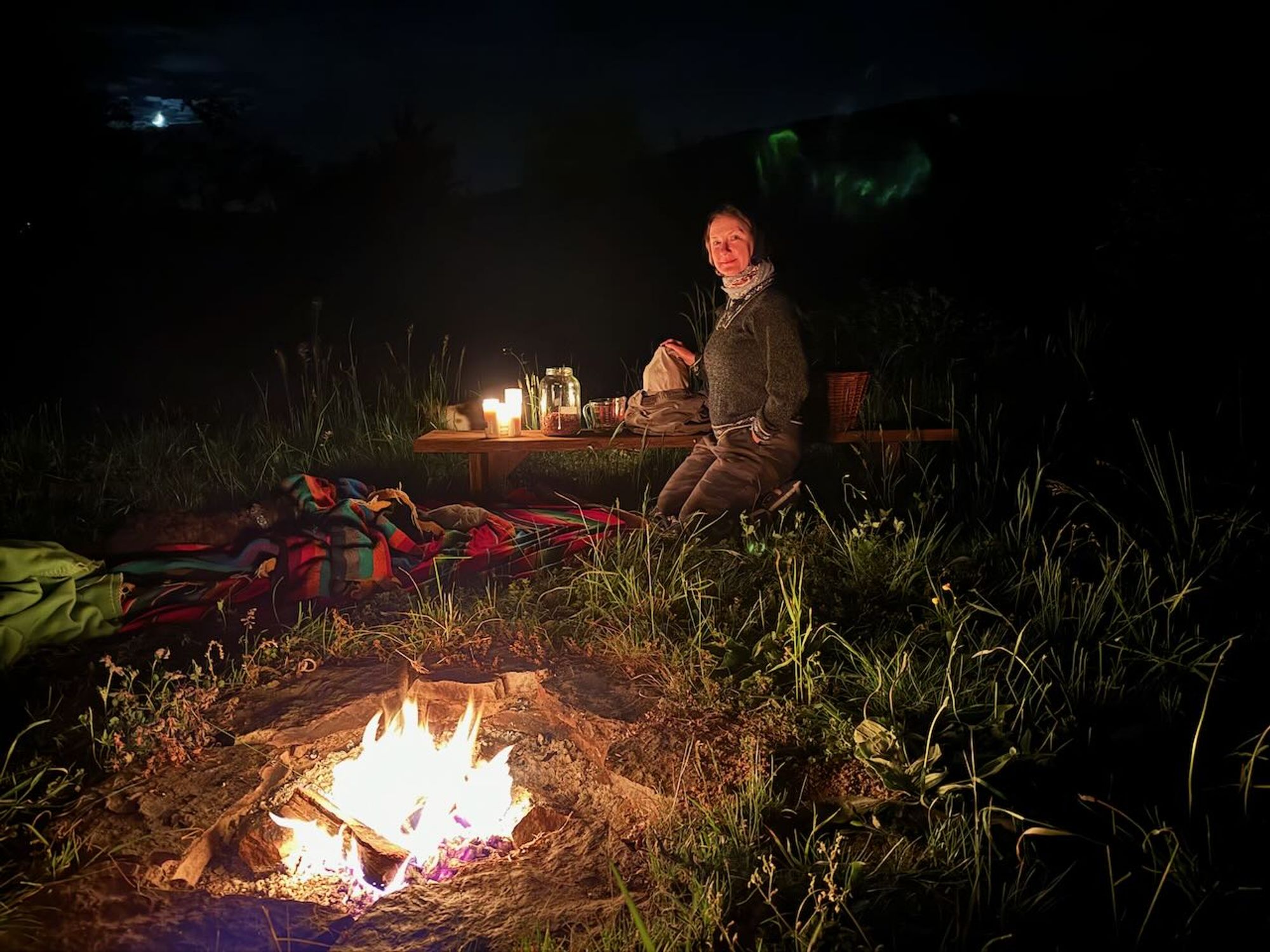 A picture of our Maker of Magical Natural Inks preparing various herbs and waters at night in front of a campfire