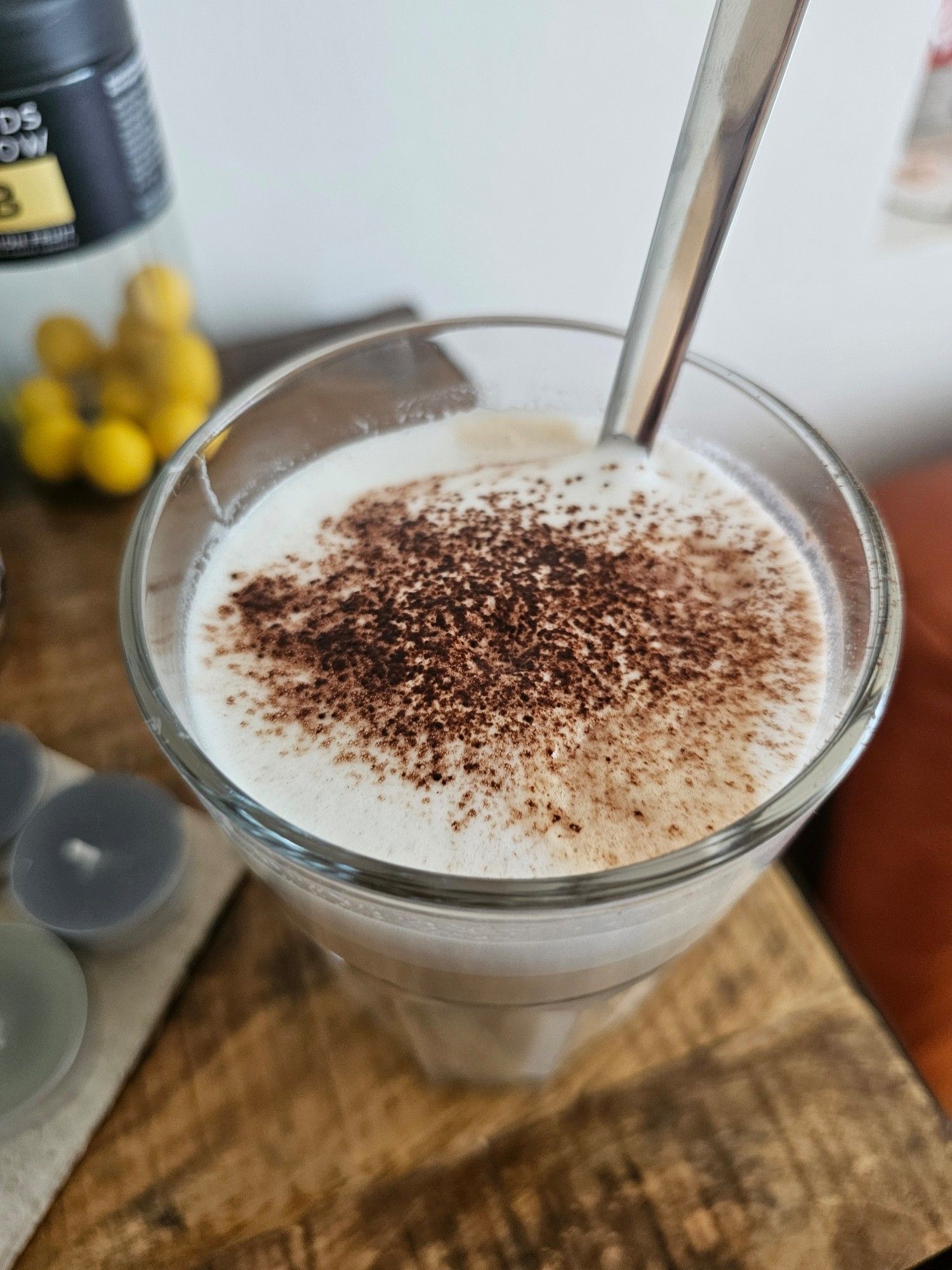 Latte-Macchiato von oben. Zu sehen ist die Oberfläche der Milch, auf der die Kakao-Streusel liegen.