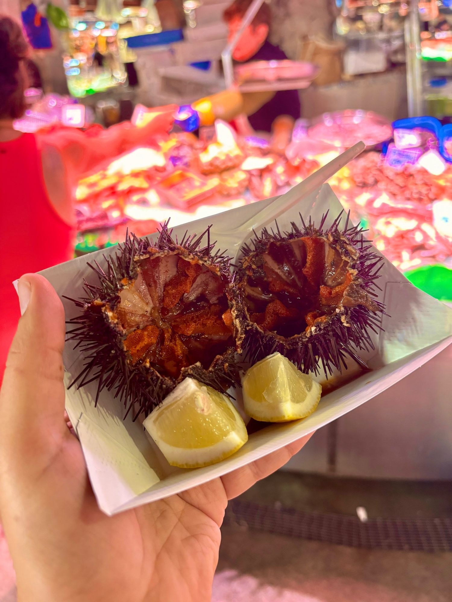 Close up of some portions of kina, or sea urchin in English. They’re small and prickly with some juicy delicate flesh in the inside. Garnish with some pieces of lemon.