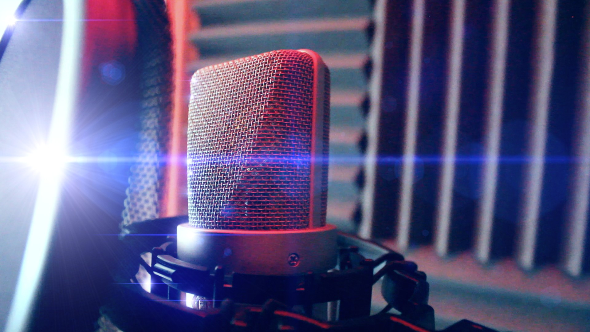 A Neumann TLM-103 large diaphragm condenser microphone, inside a vocal booth, with ridged acoustic sound insulation tiles on the walls.