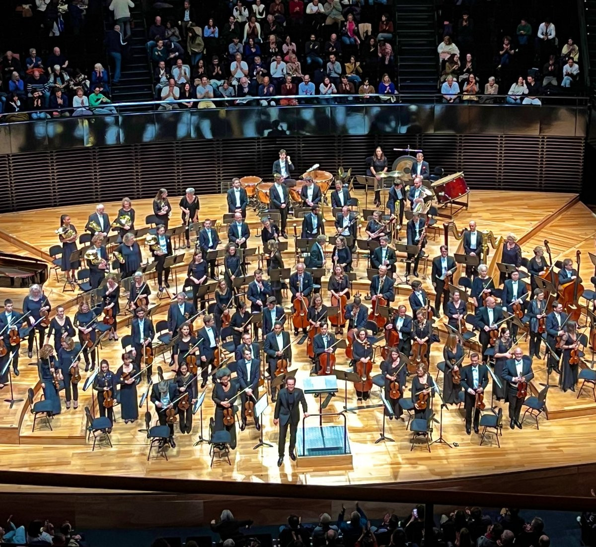 Photographie de l’orchestre et du chef d’orchestre Case Scaglione saluant le public à la fin du concert