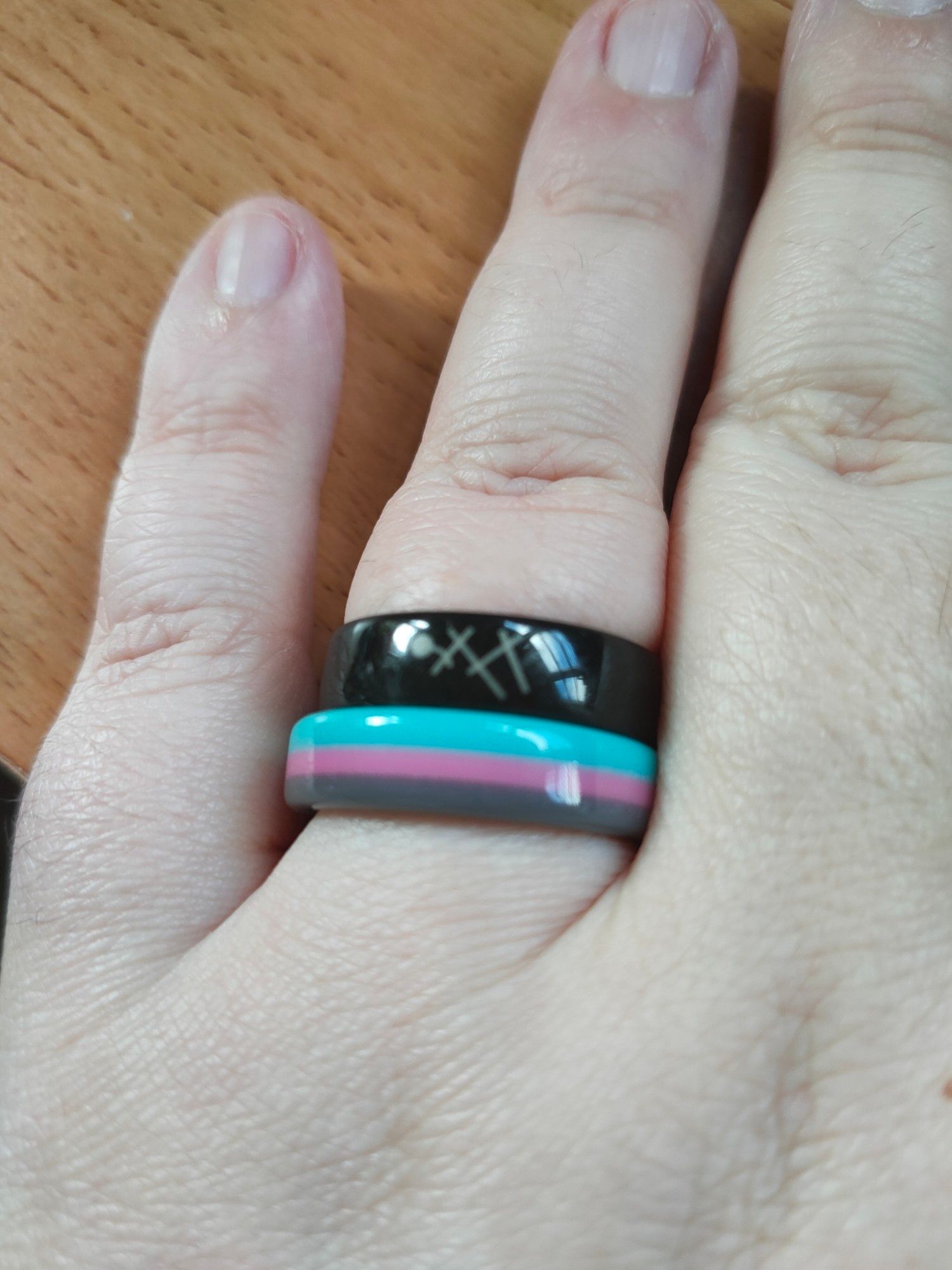 Picture of my hand with two rings; on the bottom is the Miku Piit ring and on the top is a black one with 5 grey stripes.