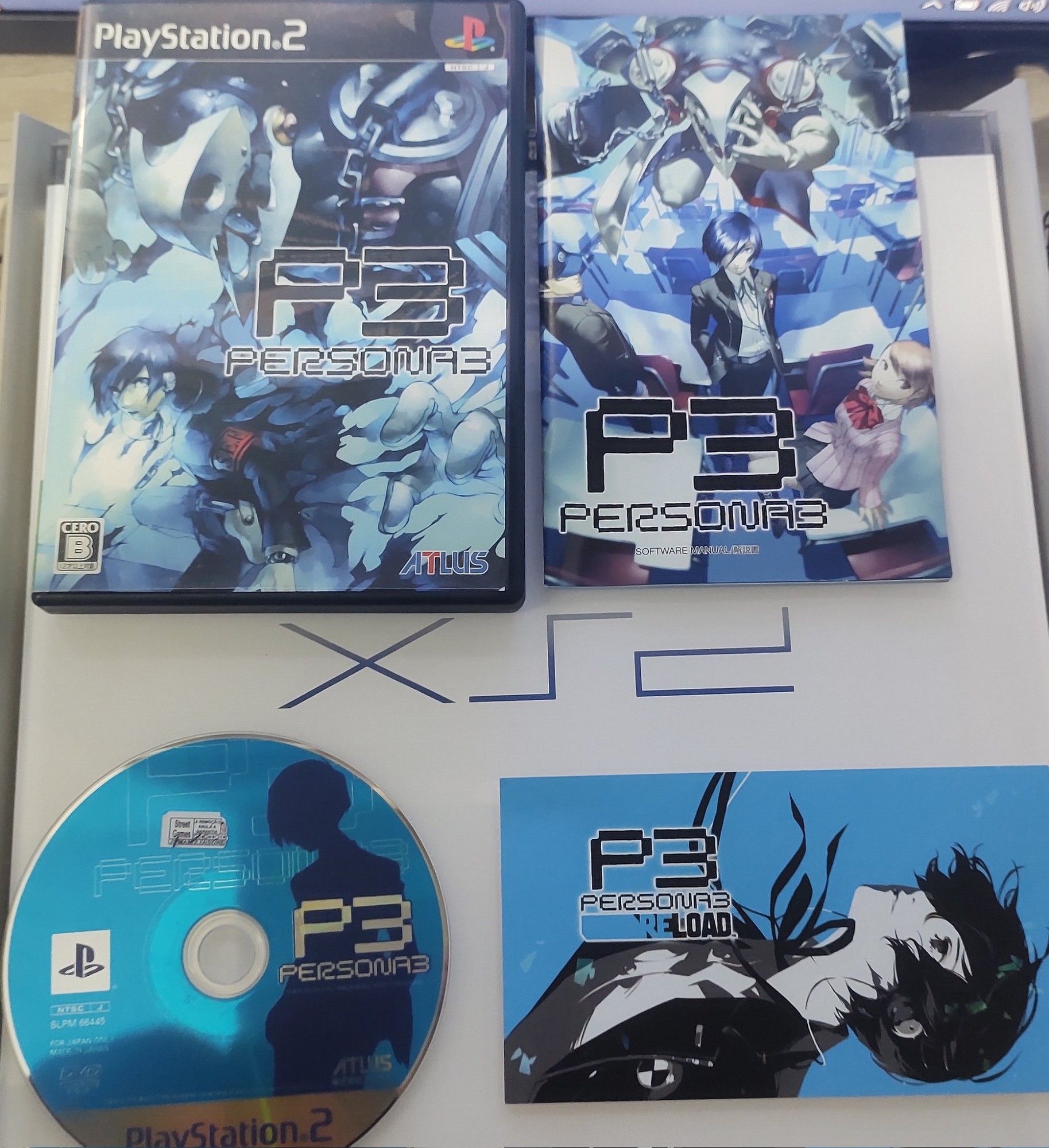 Cópia Original da primeira versão de Persona 3 (do PlayStation 2), junto de um mini-poster do Persona 3 Reload (da BGS 2023).