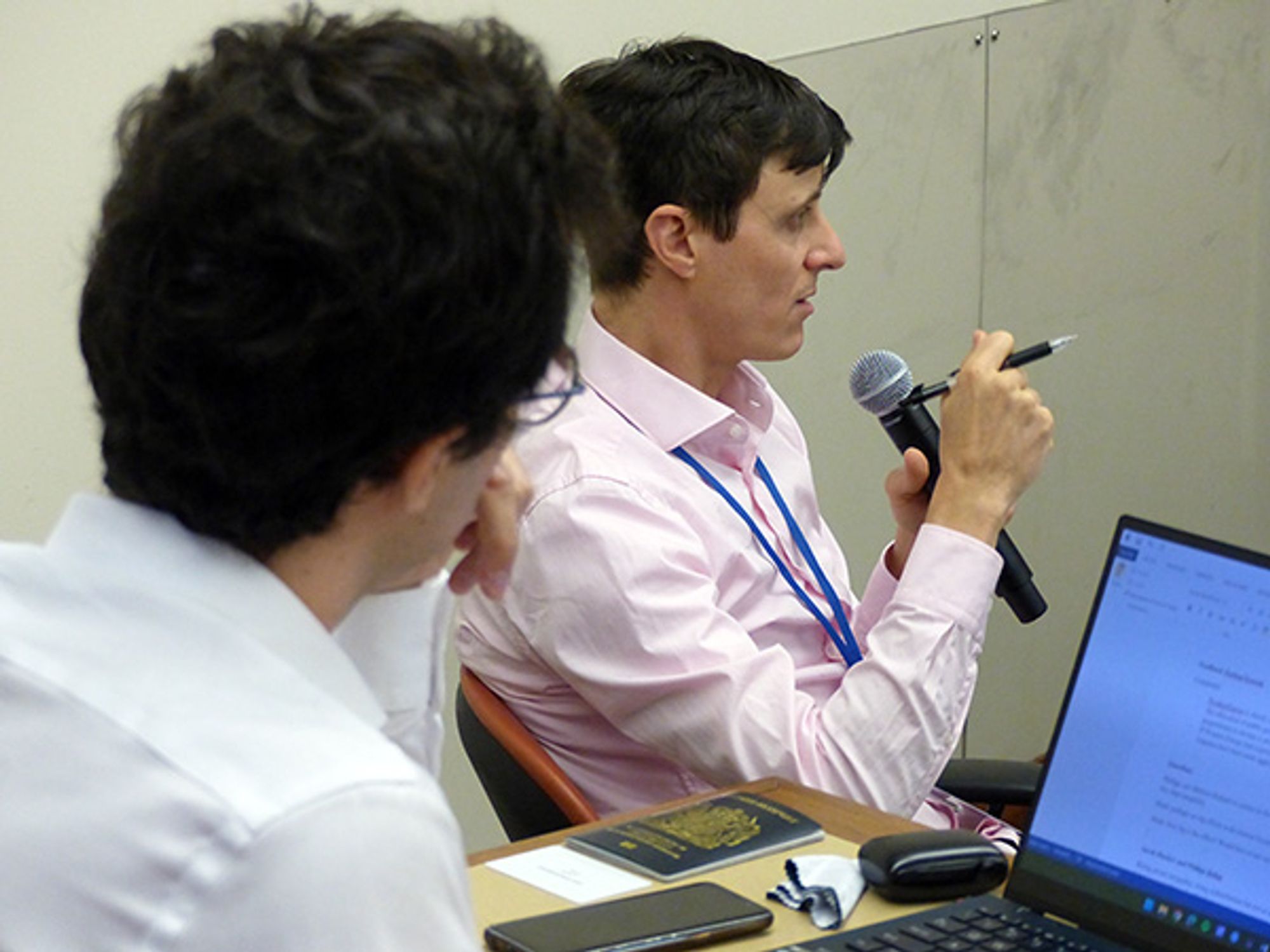 Phiipp Rehm of Johns Hopkins contributes to a lively discussion of tax policy at an ISPS APEX conference, seated, using a microphone as another participant looks on from behind