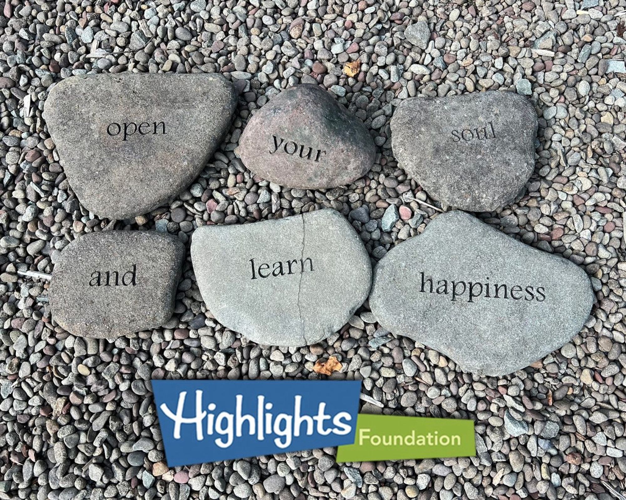 Six stones with words on them sit on pebbles in the word garden at The Highlights Foundation. Words read “open your soul and learn happiness”. Photo by Victoria K. Chapman.