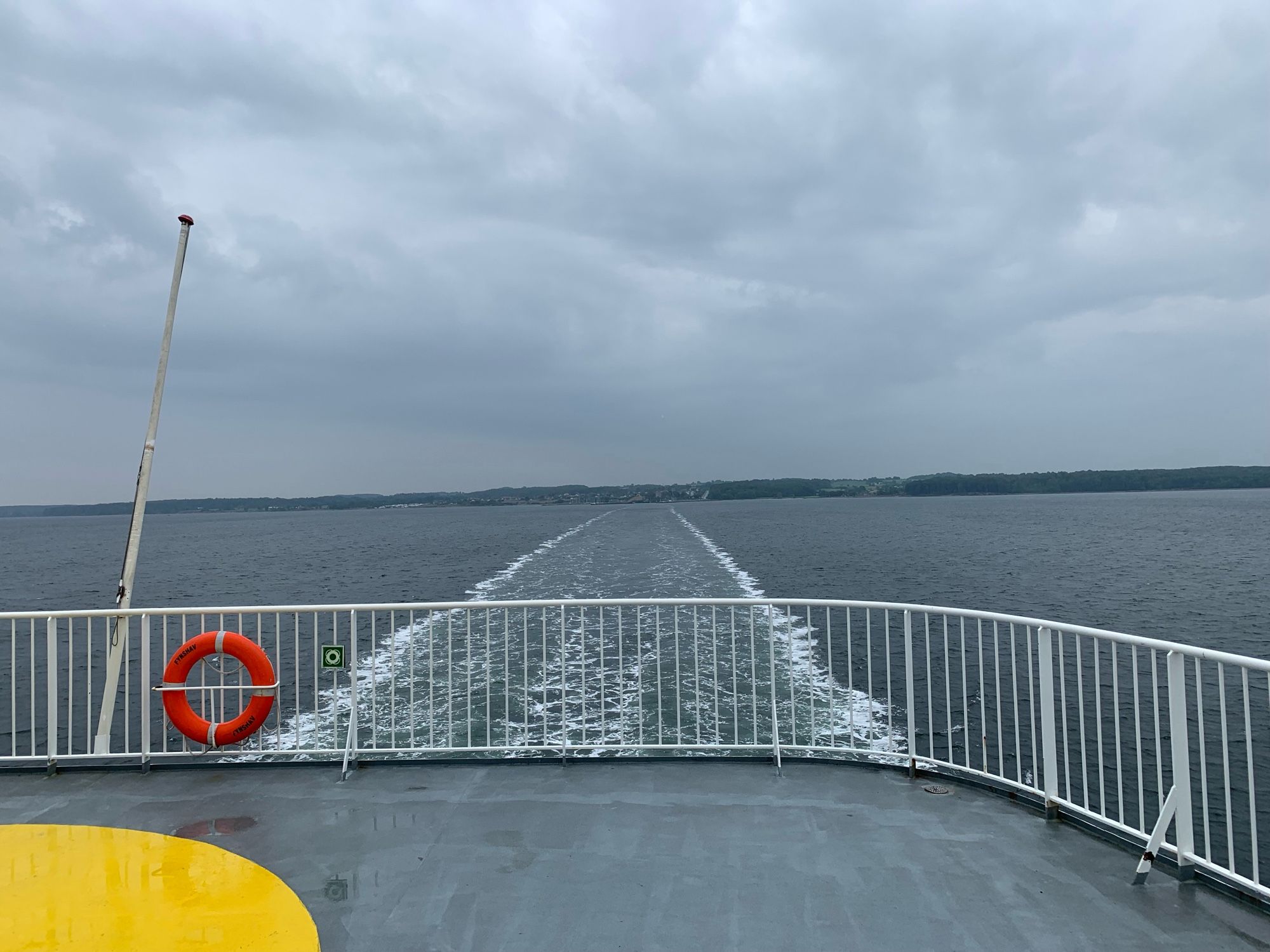 Aussicht vom Heck des Schiffes aufs Wasser und die Küste im Hintergrund