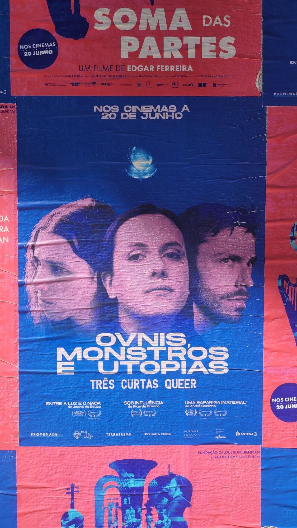 Poster bleu et rose fluo annonçant la sortie de 3 courts métrages queer portuguais "ovnis, monstros et utopias".
Photo prise dans les rues de Lisbonne