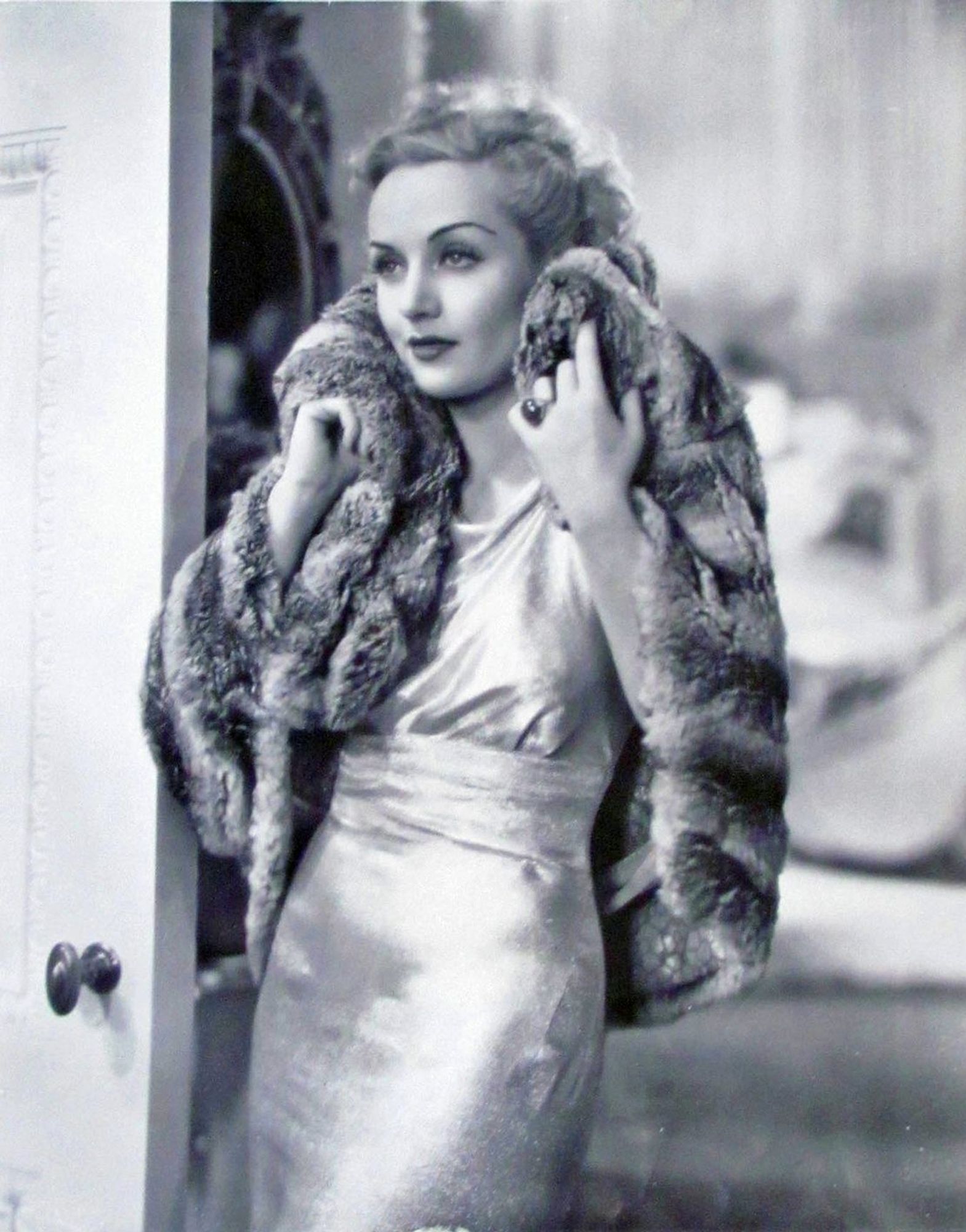 A still from Twentieth Century, Carole Lombard wearing a spectacular (possibly silver lame) dress and chinchilla coat