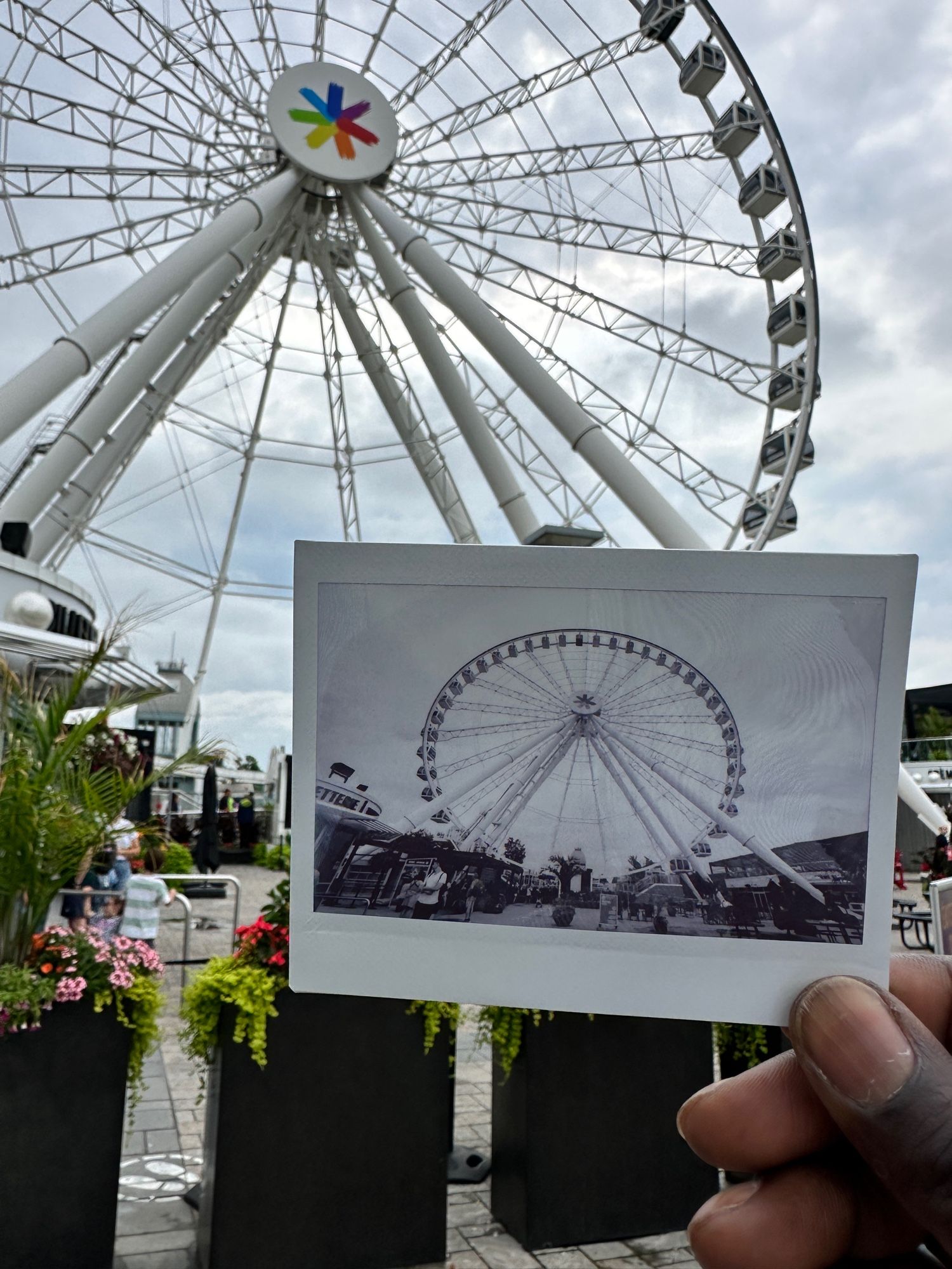 a monochrome instax wide photo of a ferris wheel next to the actual ferris wheel. 