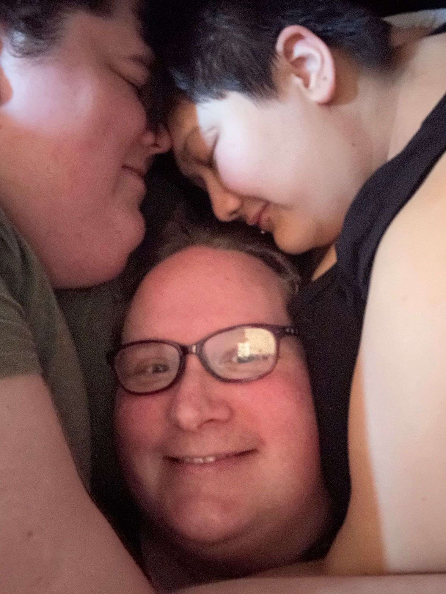 Me and my wife and our partner in a cuddle puddle, my head between two glorious sets of tiddies. We’re clothed, so it’s SFW