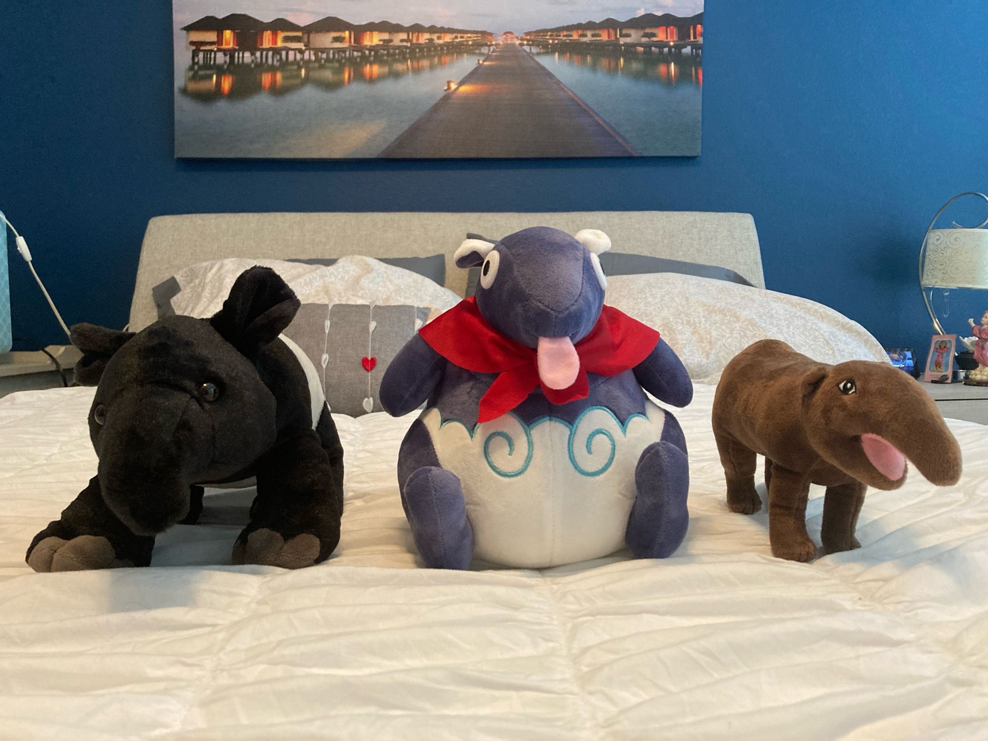 A trio of tapir plushies on top of a soft mattress.