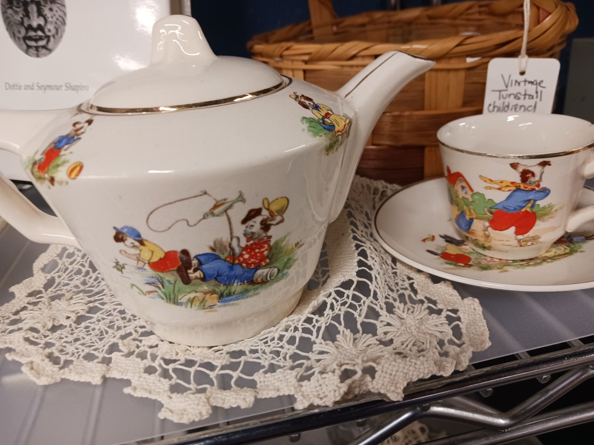 A 1930s child's high end porcelain tea set with puppies in human clothes fishing, running, and playing games on all the dishes