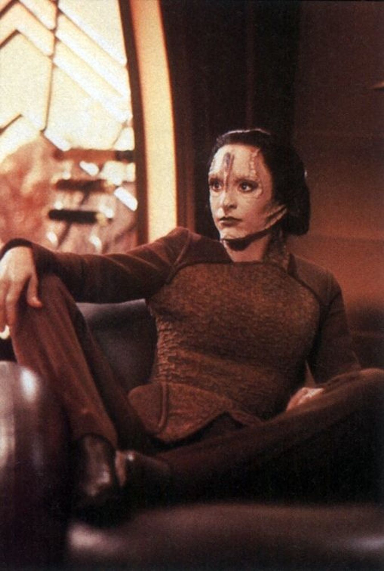 Major Kira but as a Cardassian, sitting on a comfy chair with her legs spread in a dominant fashion, she is having NONE of your shit.