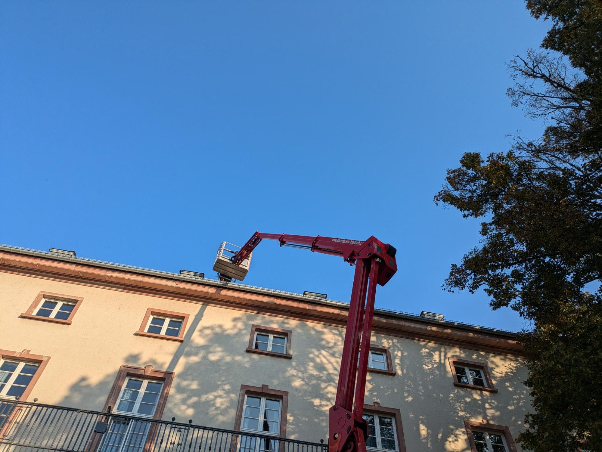 Himmel und teilweise Gebäudeansicht. Im Vordergrund eine Hebebühne.