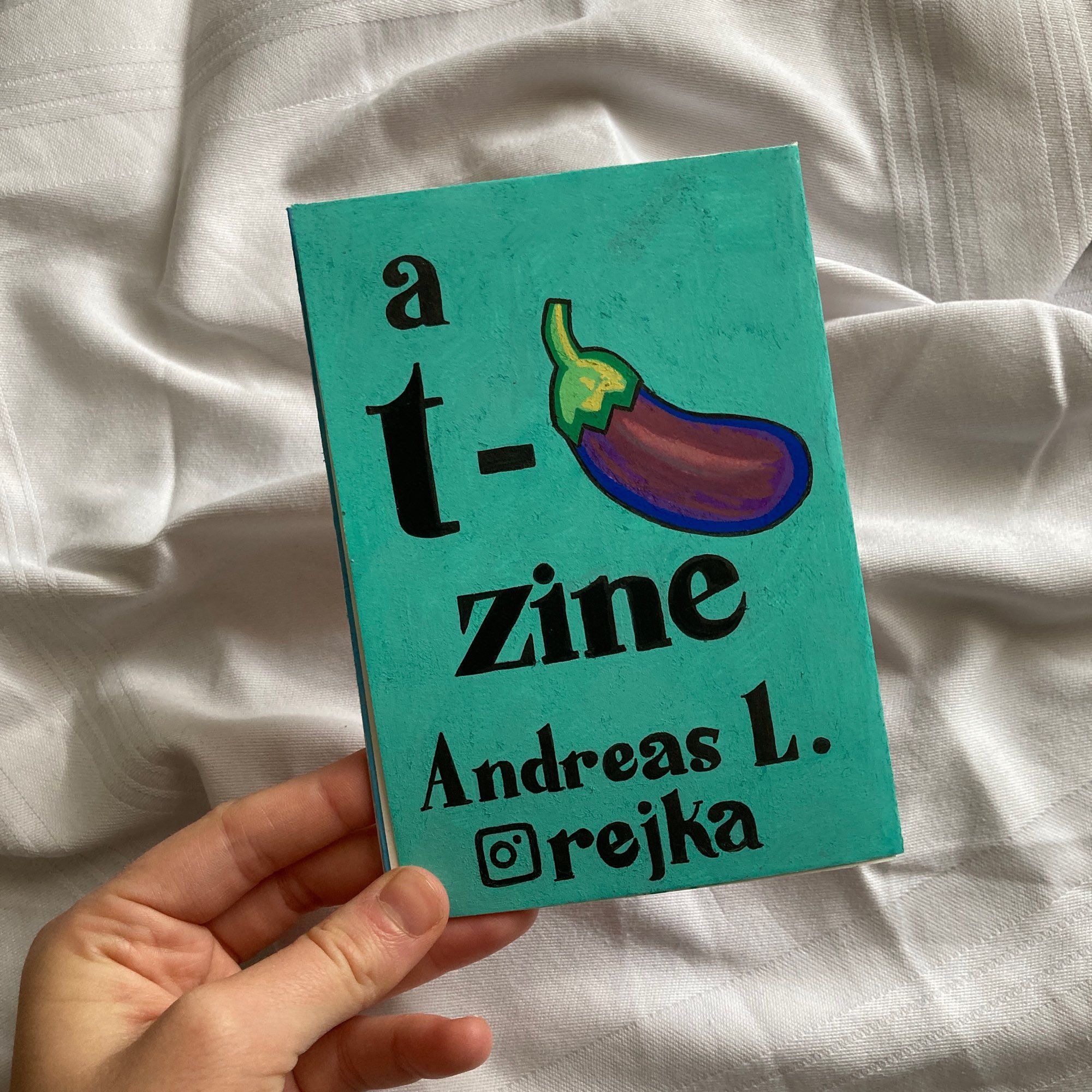 The back cover of the zine with the words “a t-🍆 zine, Andreas L., instagram rejka” on a turquoise background