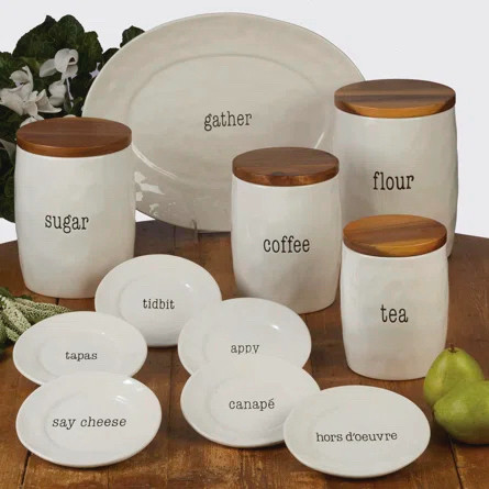 a display of white ceramic kitchen wares with words on them like “flour”, “tea”, “canapé” etc