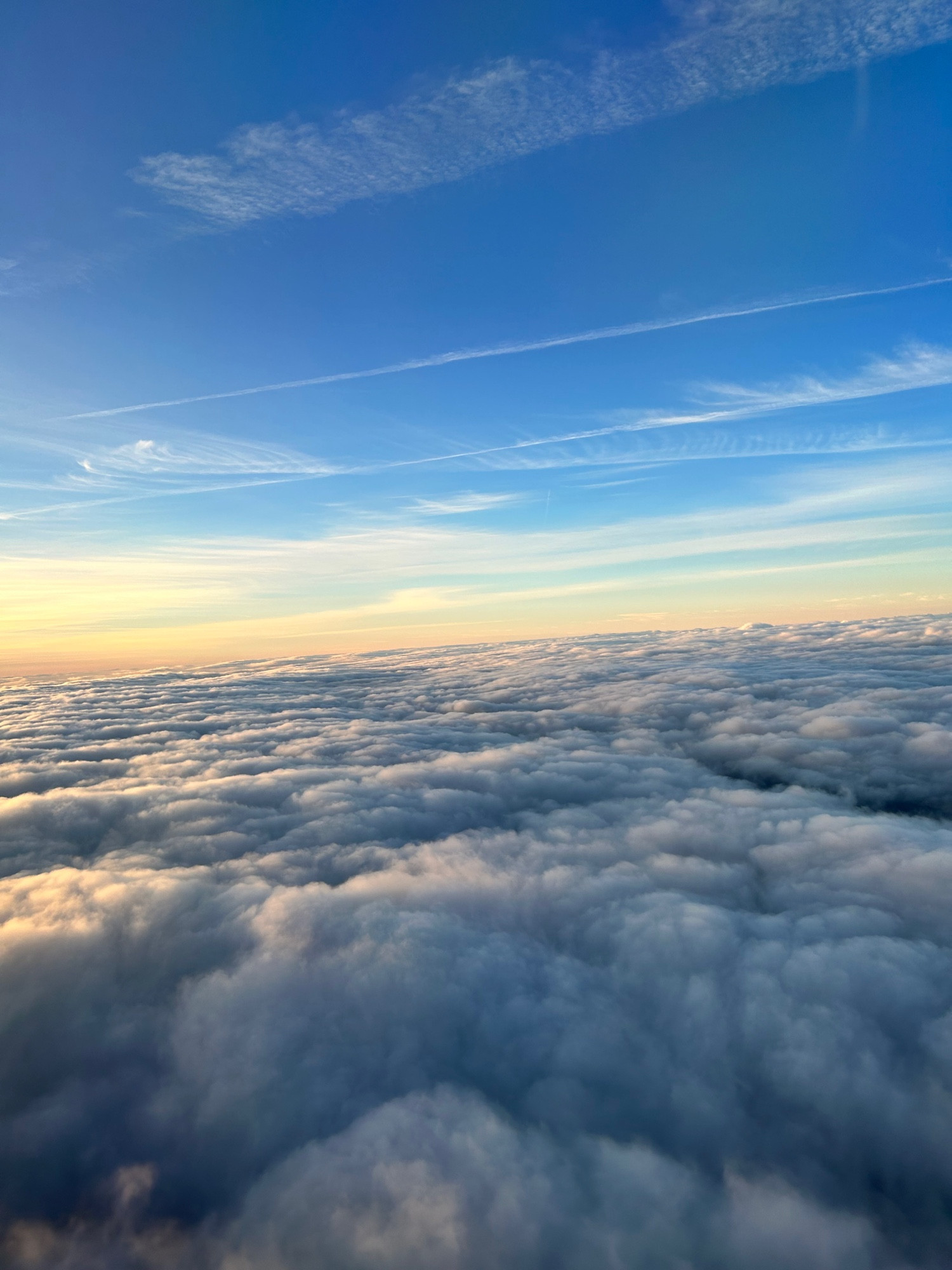 Foto de las nubes hecha desde un avión, parece un mar de nubes tocadas por los despuntes del rayo de sol