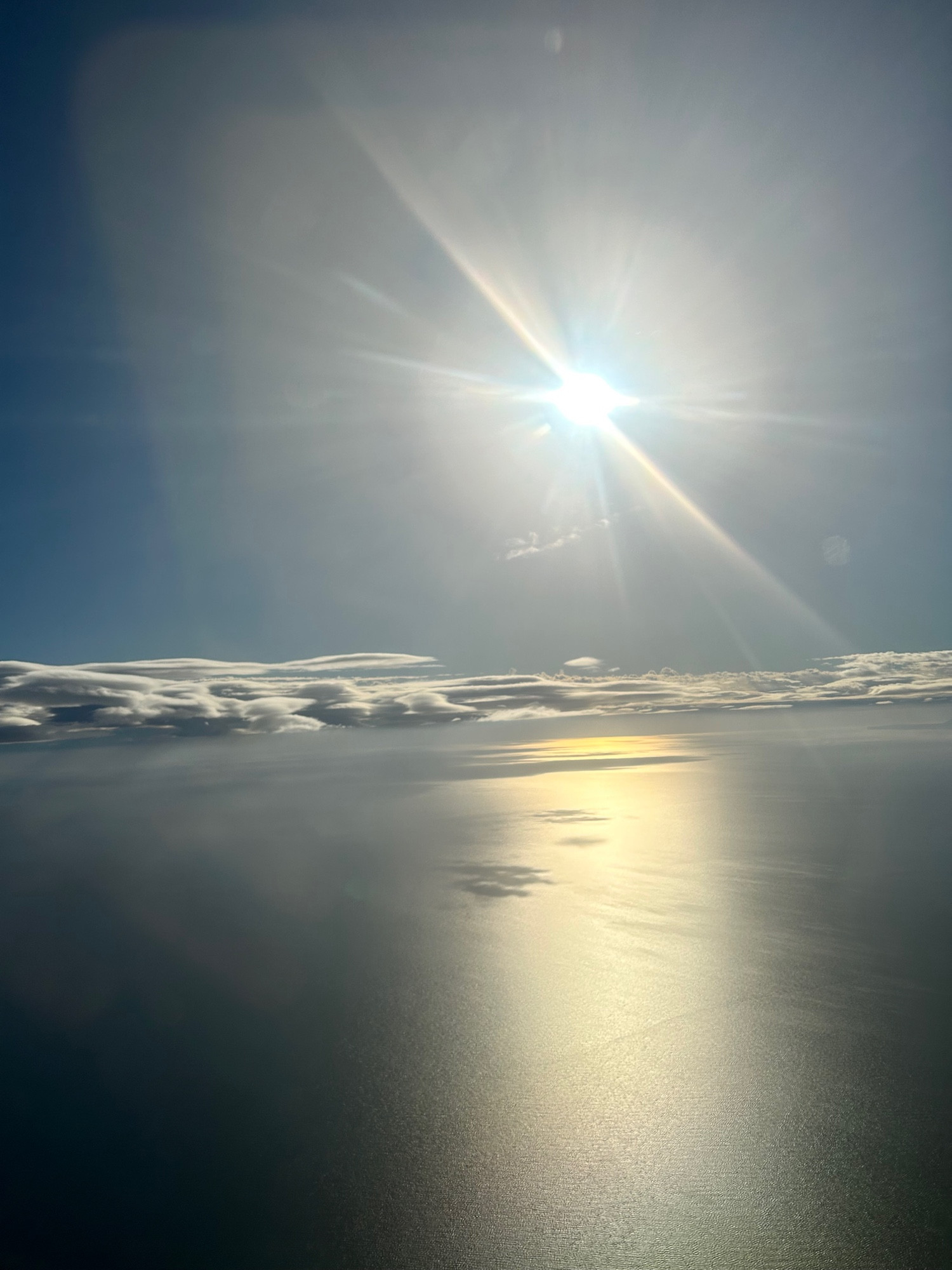 Foto del mar desde el avion, el sol se refleja en el mar y el cielo y el agua hacen un mismo degradado